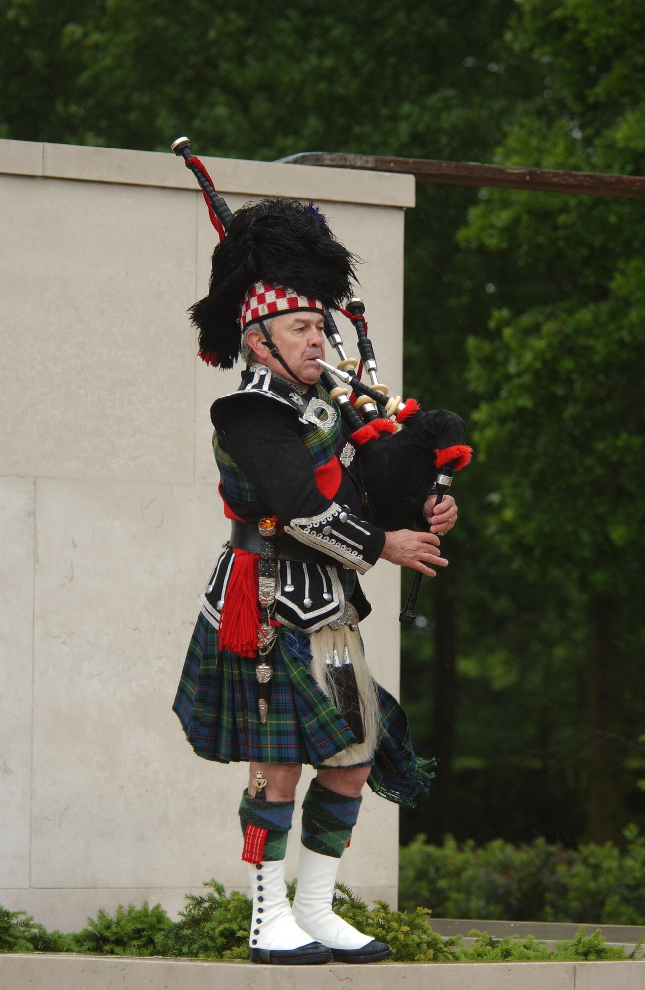 As a tribute to the men and women honored at the World War II American Cemetery, in Cambridge, Gary Kernaghan performs on the bag pipes despite the downpour during the annual Memorial Day ceremony, May 28, 2007.
(USAF Photo by: Tech. Sgt. Tracy L. DeMarco)