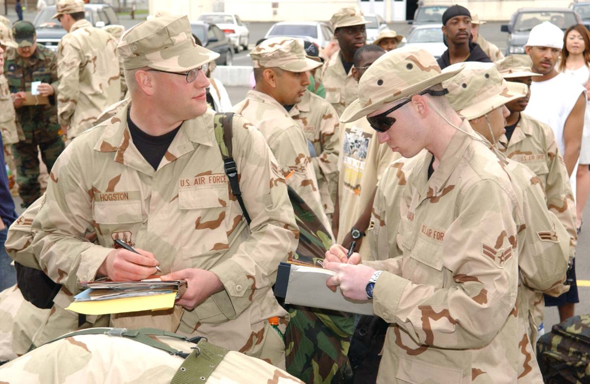 070526-F-0108B-004 MISAWA AB, JAPAN -- Airmen First Class Daniel Hogston (left), and Anthony Sullivan (right), join dozens of other deploying Misawa servicemebers filling out their baggage tags before processing into the base terminal May 26, 2007.  More than 500 servicemembers deployed for Air Expeditionary Force 7 and 8, making it the largest deployment the base has undertaken in support of Operation Iraqi Freedom. (U.S. Air Force photo by Senior Airman Robert Barnett)