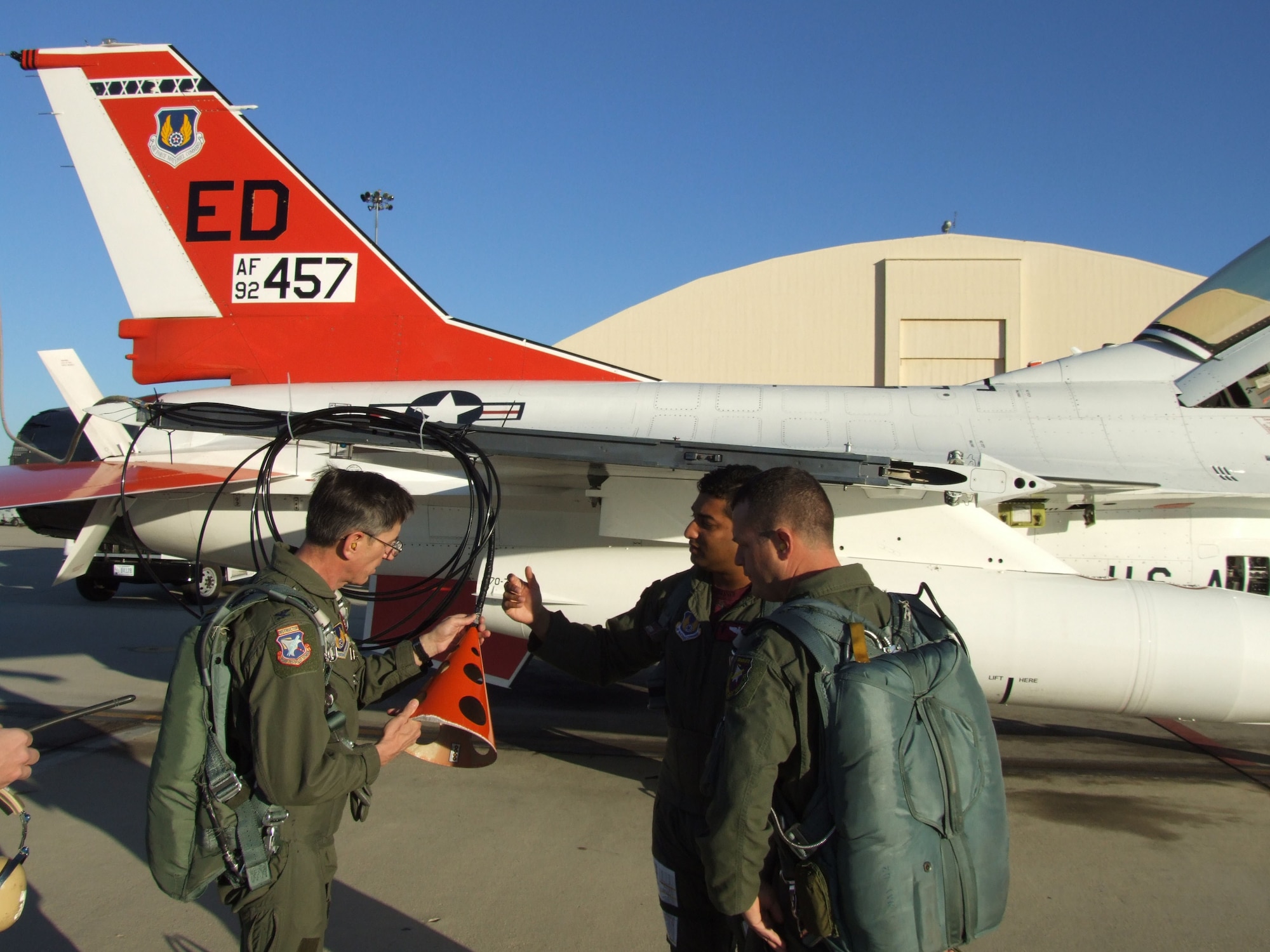 Col. Andre Gerner (left), U.S. Air Force Test Pilot School commandant, checks out an F-16B trailing cone assembly, as Maj. Swami Iyer (center), test pilot, and Lt. Col. Dean Ward (right), TPS operations officer, look on. (Courtesy photo)