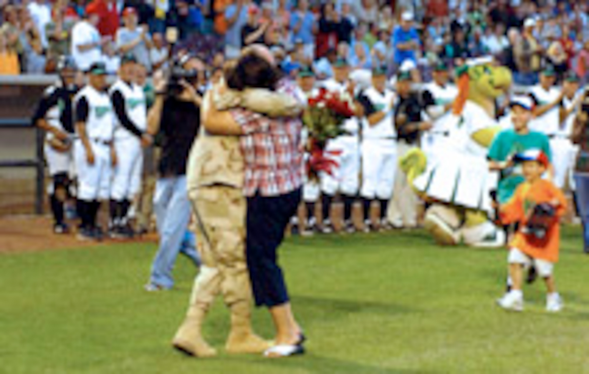 In a surprise reunion, Kim Thigpen embraces her husband, Capt. Jim Thigpen, as their sons, Jacob and Caleb run across Fifth Third Field in Dayton, Ohio. The captain is a member of Aeronautical Systems Center's 726th Aeronautical Systems Group at Wright-Patterson Air Force Base, Ohio, which manages the B-2 Spirit. (Courtesy photo/Dayton Dragons) 
