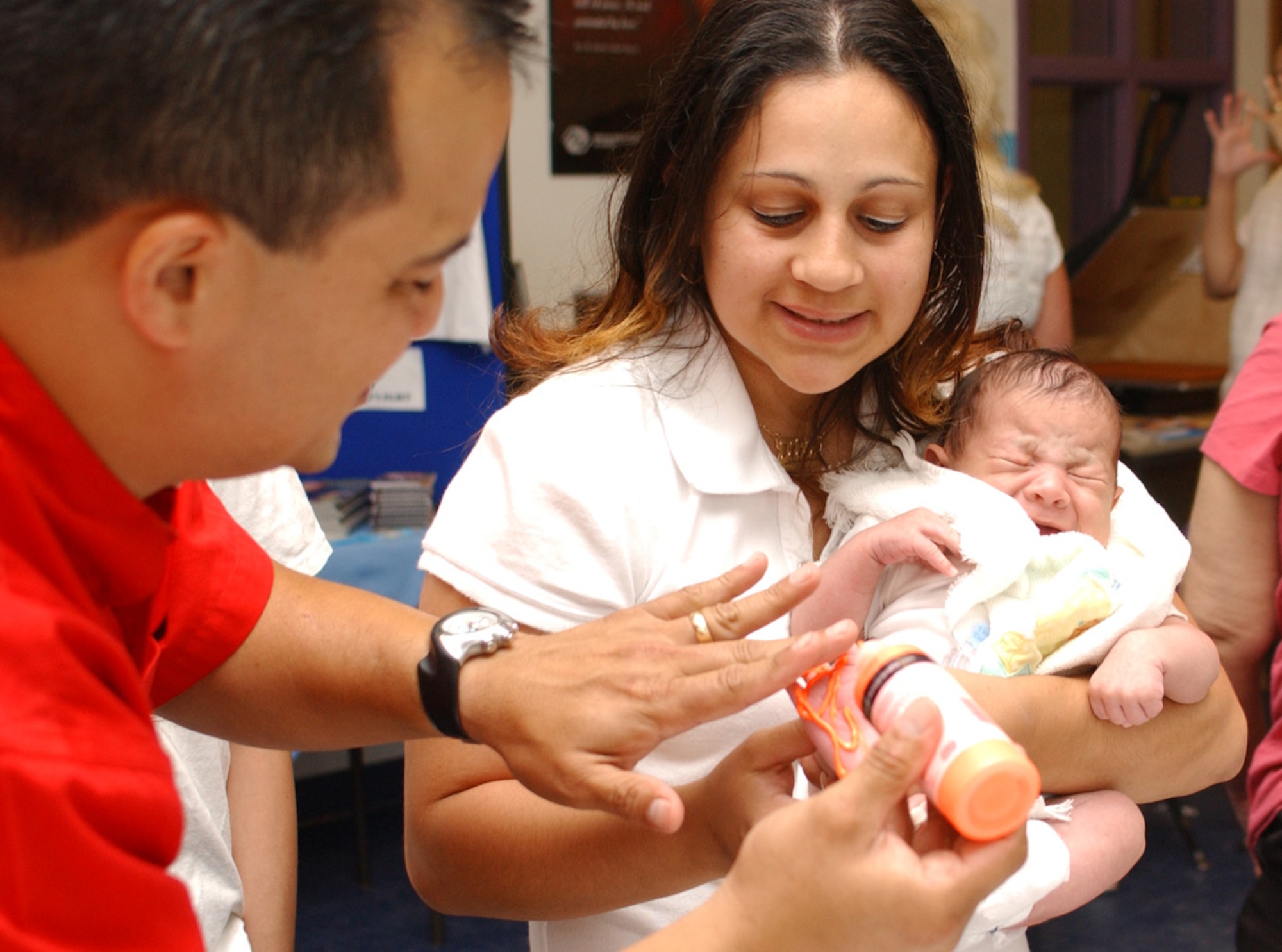 Tech. Sgt. Ernesto Alvendia, readiness noncommissioned officer in charge at the airman and family readiness center, puts paint on the foot of 1-month-old Angel Carra-squillo as he’s held by his mom, Idaliz.  Angel’s footprint was placed on a pillowcase for his father, Tech. Sgt. Roberto Carrasquillo, 81st Transportation Squadron, who’s on a remote assignment to Kunsan AB, Korea.  (U. S. Air Force photo by Kemberly Groue)