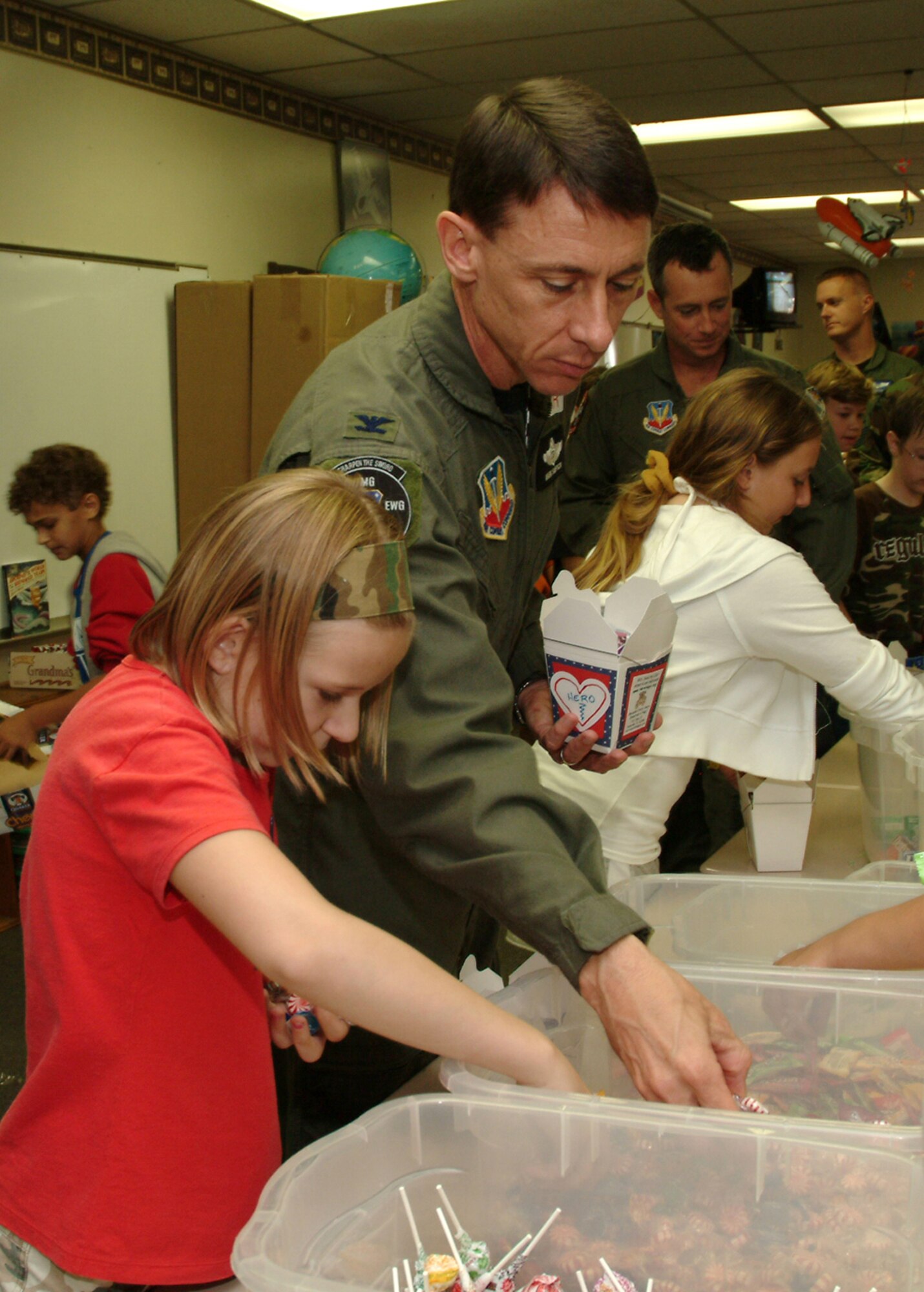 EGLIN AIR FORCE BASE Fla. -- Bailey Reese, 5th grader at Longwood Elementary, helps Col. Mark Simpson, 53d Wing vice commander, fill a couple of oriental food to-go boxes with treats for deployed Airmen. The 11-year-old is the founder and president of America Supports You grassroots organization, Hero Hugs, that allows children to send appreciation packages to deployed personnel. The students and Airmen from the 53d worked together to fill more than 300 boxes to be shipped to Iraq and Afghanistan. (U.S. Air Force photo/Tech. Sgt. Andrew Leonhard)