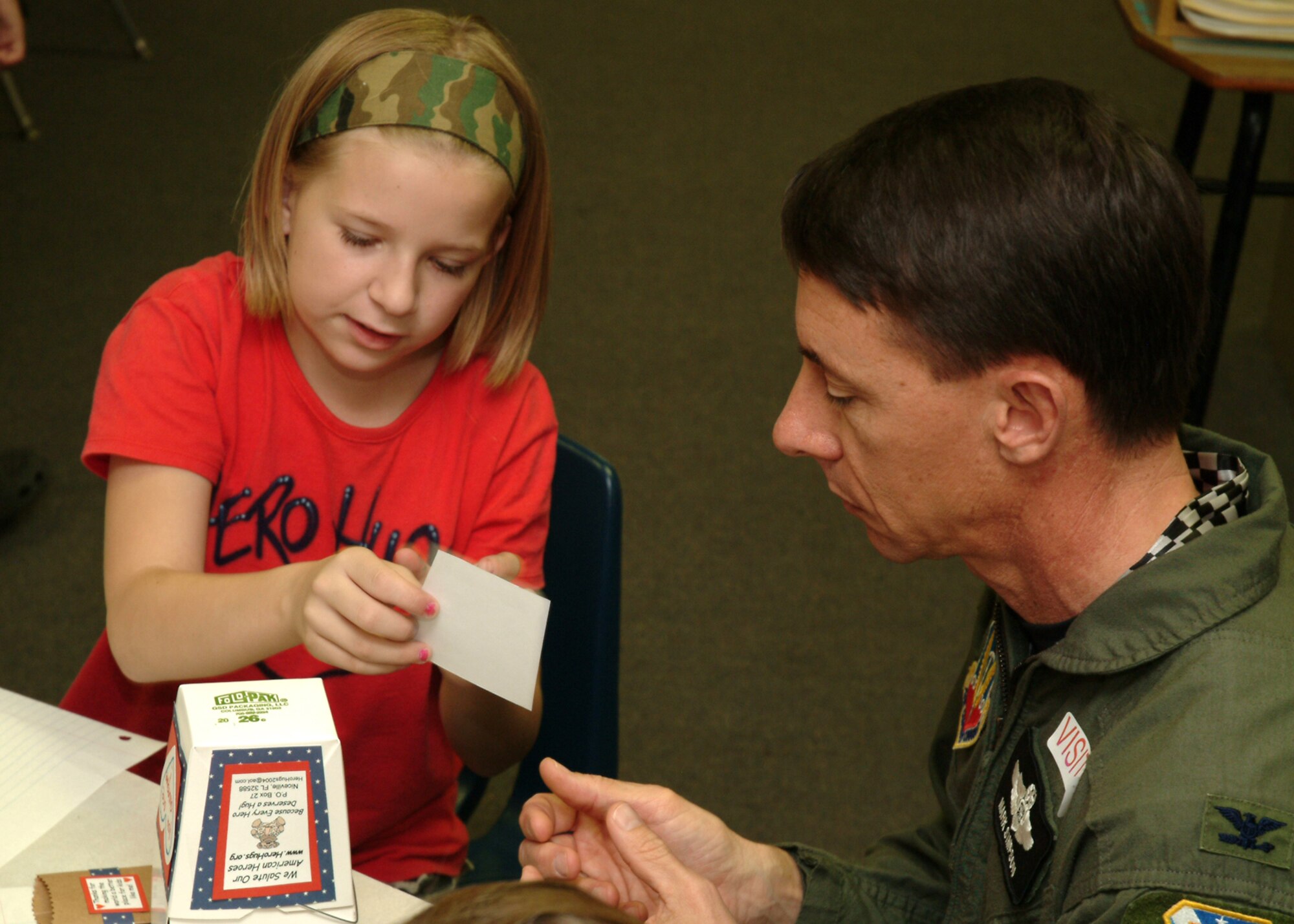 EGLIN AIR FORCE BASE, Fla. -- Bailey Reese, Longwood Elementary 5th grader, shows Col. Mark Simpson, 53d Wing vice commander, how to decorate his oriental food to-go box prior to filling it with treats to send to deployed Airmen. The 11-year-old is the founder and president of America Supports You grassroots organization, Hero Hugs. Ms. Reese, her classmates and Airmen from the 53d Wing, worked together to fill more than 300 boxes to be shipped to Iraq and Afghanistan. (U.S. Air Force photo/Tech Sgt. Andrew Leonhard)