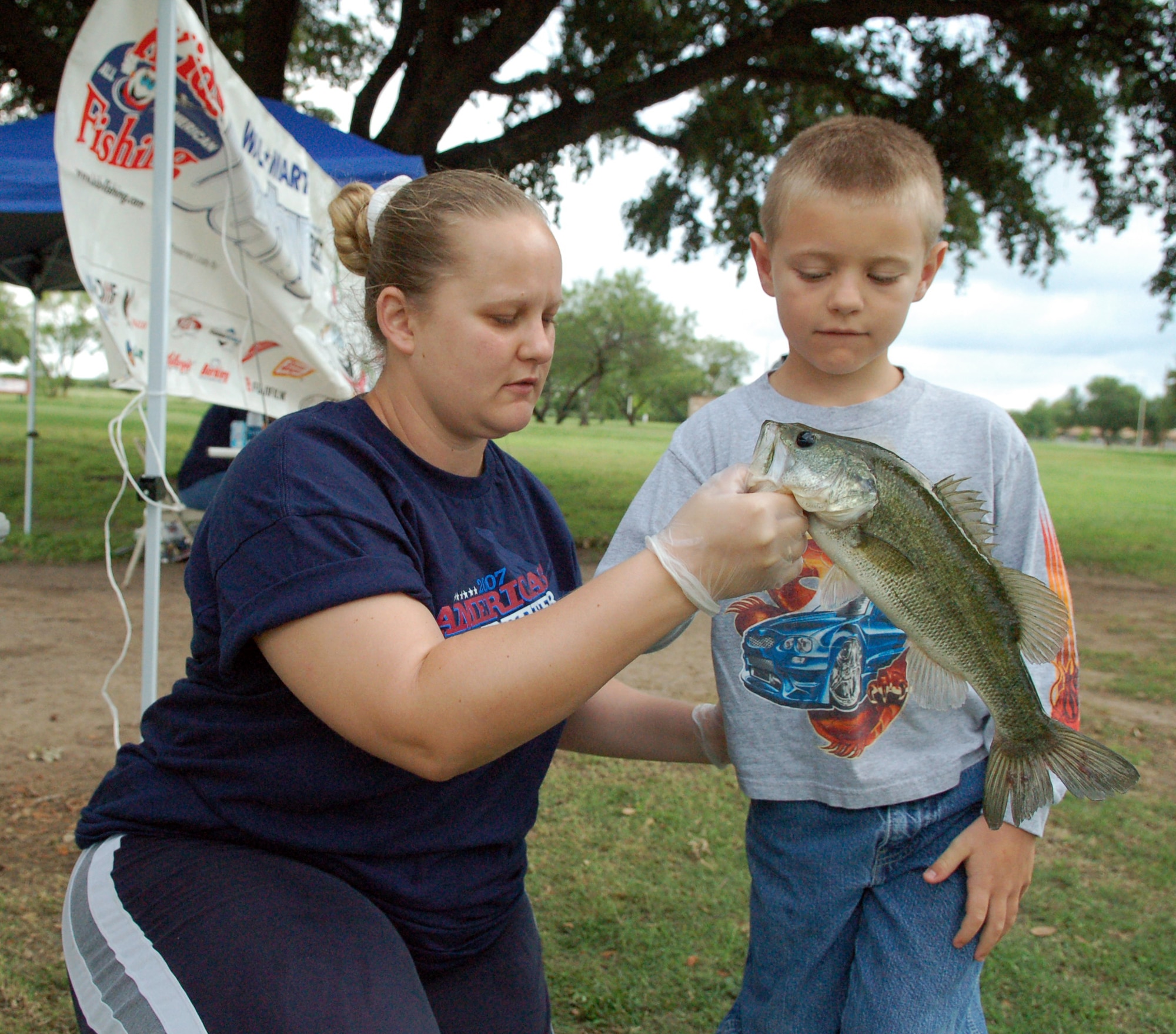 LAUGHLIN AIR FORCE BASE, Texas --  April Shobe, 47th Force Support Squadron youth programs and sports director, shows Christian Waterman, 7, son of Maj. Kervin Waterman, 84th Flying Training Squadron, how to hold his 15-inch bass.  (U.S. Air Force photo by Staff Sgt. Austin M. May)