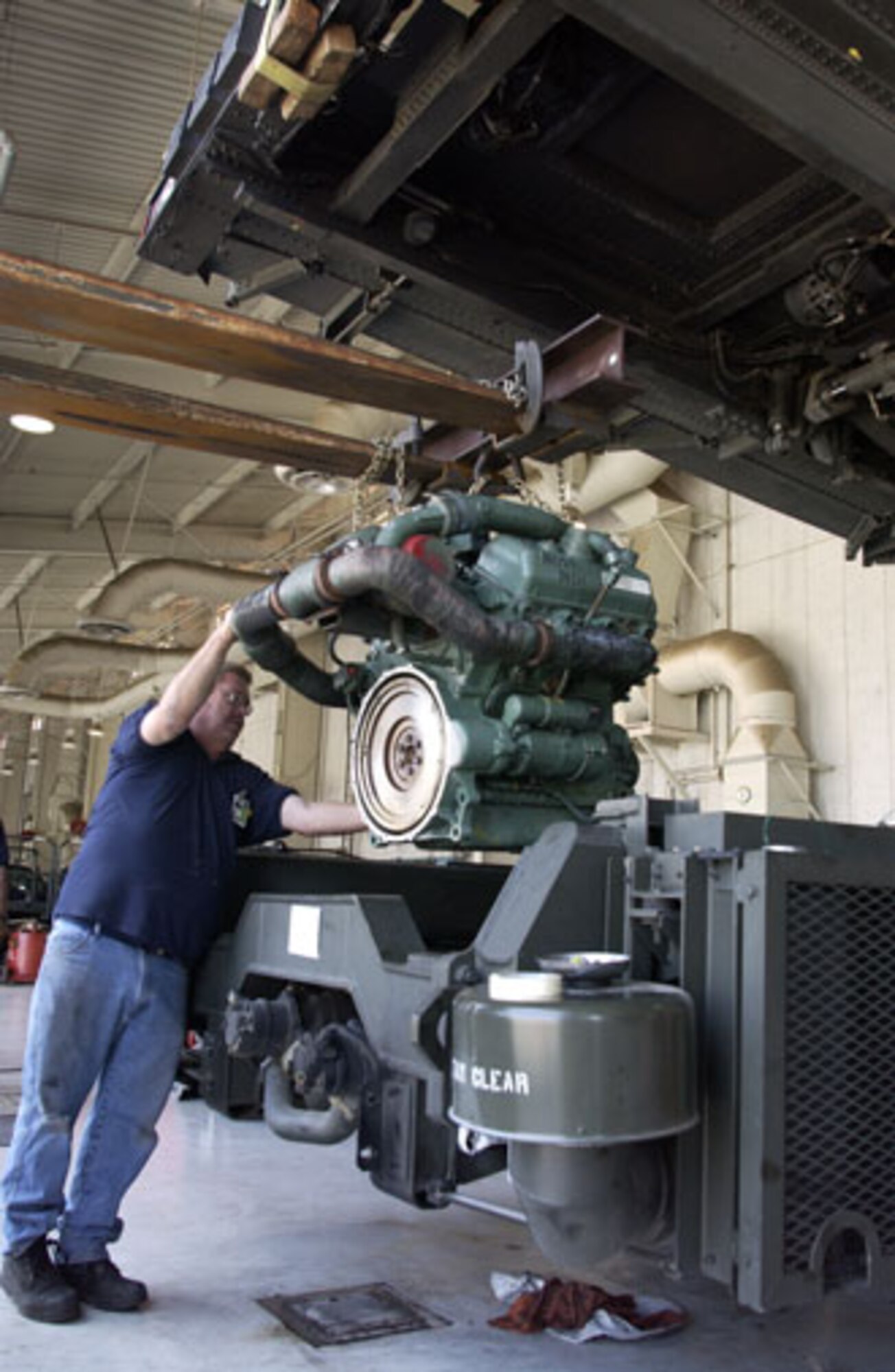 Tom Gillis, a contractor with Satellite Services, Inc., helps remove the engine on a Tunner 60K loader before replacing it with a new $40,000 engine. This is the first time since March has owned their Tunners that this procedure has ever taken place. It is a Detroit Diesel, 6 cylinders 350 HP, 5.3 Liter Engine weighing roughly 1700 lbs. Gillis, Fred Caluya, also a contractor, and Tech Sgt. Chan Sivon, an SSI trained reservist with the 452nd Logistics Readiness Squadron, worked for over a week to ensure the Tunner was operable and ready to work again and, in the process, gained some valuable training. (U.S. Air Force photo by Amy Abbott)