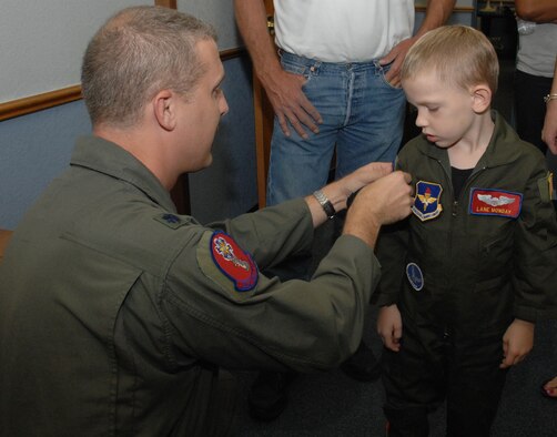 Lt. Col. Paul Bauman, 58th Airlift Squadron commander, gives Lane Monday his official 58th AS patch to go with his flight suit during the Pilot for a Day program tour. (U.S. Air Force photo/Senior Airman Mercedes Crossland)