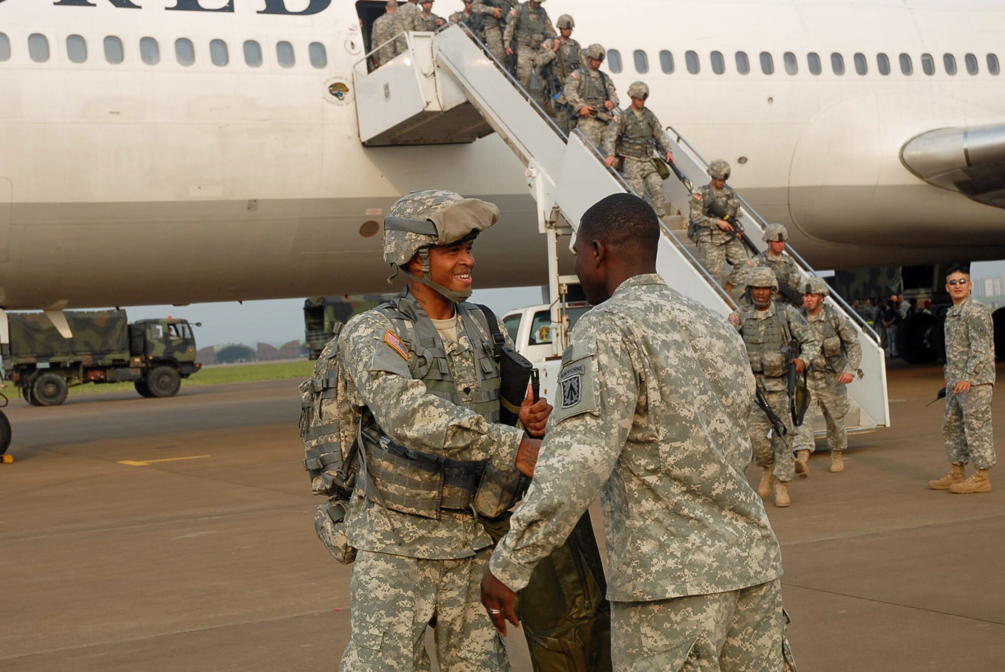 SUWON AIR BASE, Republic of Korea --  A soldier with 1st Battalion, 7th Air Defense Artillery, 108th ADA Brigade is greeted moments after setting foot on Korean soil by a fellow soldier from his battalion who arrived a week prior. (U.S. Army photo by Pfc. Gretchen N. Goodrich)