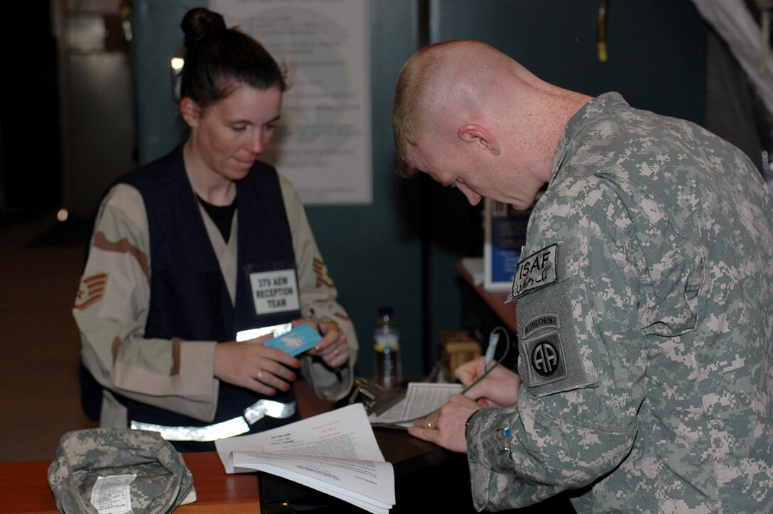 Staff Sgt. Laura Fournier assists Army Capt. Samuel Morgan who has just arrived at this Southwest Asia air base.  Sergeant Fournier, the 379th Expeditionary Services Squadron lodging supervisor, serves on the reception control team to provide assistance to transient personnel moving on to other duty locations. Reception control team members wear blue vests for easy identification.  (U.S. Air Force photo/Senior Airman Erik Hofmeyer) 