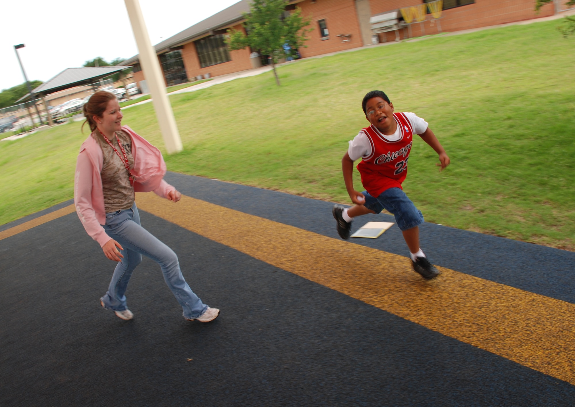 Danielle Pierce, a recreational assistant with the Madrigal Youth Centers summer camp, plays freeze-tag with Lamont Nesbitt June 5. (U.S. Air Force photo/Airman 1st Class Jacob Corbin)