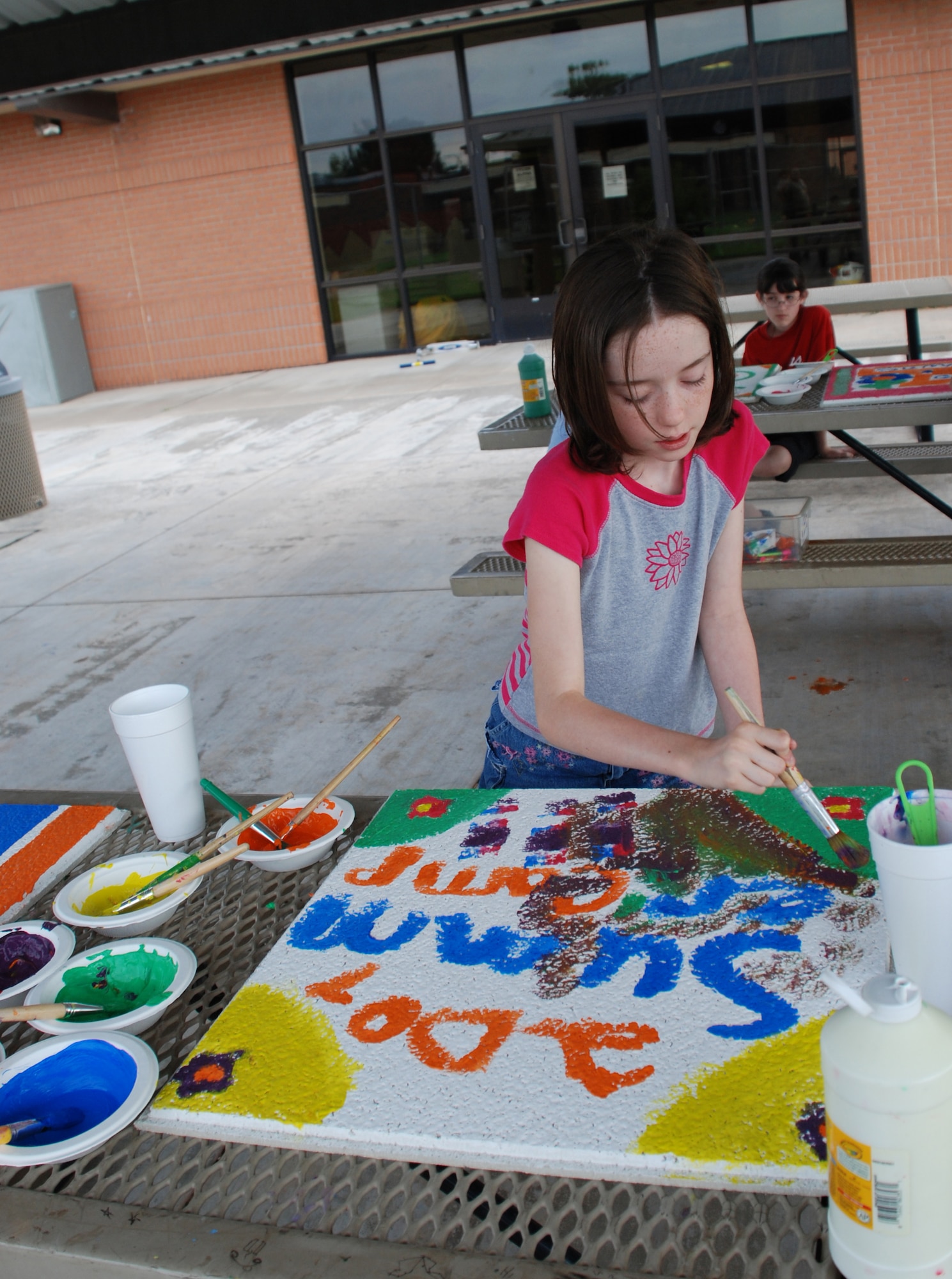Cheyenne Haney paints a ceiling tile at the Madrigal Youth Centers summer camp June 5. The children attending the camp are painting the tiles to be put in the centers ceiling. (U.S. Air Force photo/Airman 1st Class Jacob Corbin)