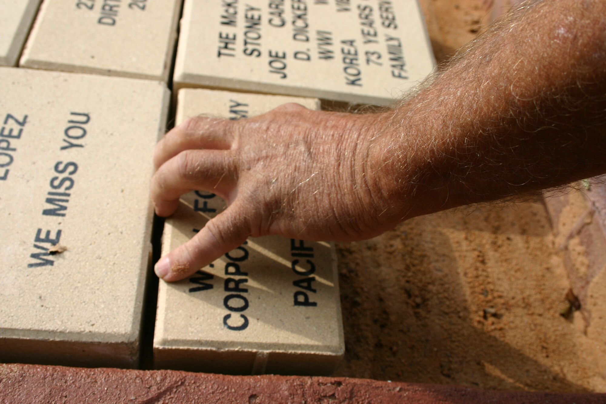 Bill Richter, 27th Civil Engineering Squadron, places a memorial brick at the Bataan Memorial. June 6 marked the one-year anniversary of the dedication of the memorial at Cannon Air Force Base. (U.S. Air Force photo by Airman Elliott Sprehe)