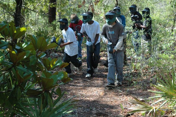 A group of boys from the youth center apply strength in numbers tactics to team up and locate Airmen from the 96th Security Forces Squadron investigations team during a friendly game of paintball. (Air Force photo by Staff Sgt. Mike Meares) 