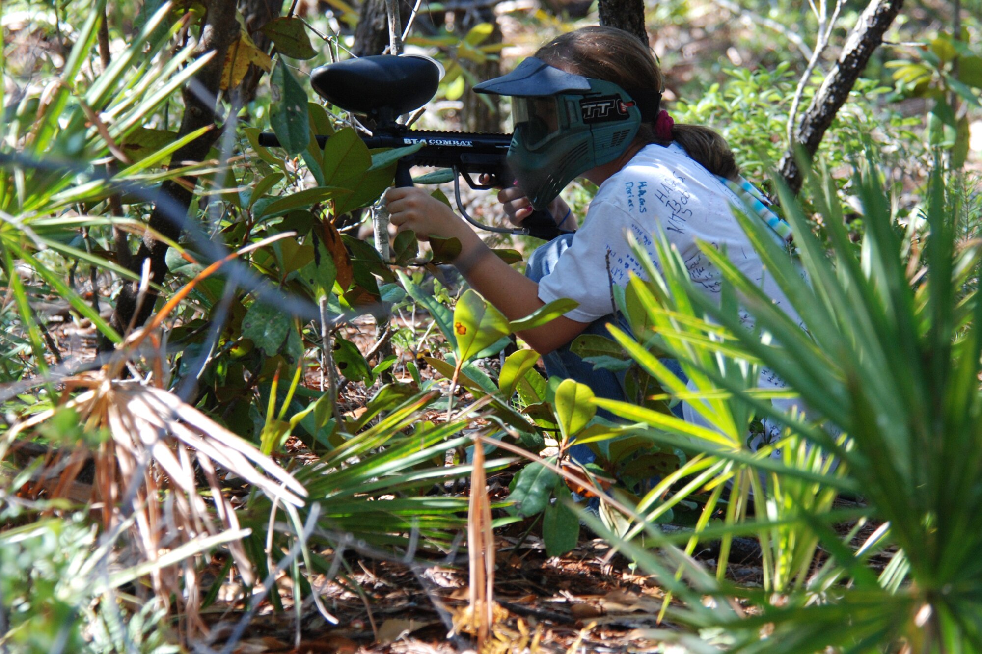 EGLIN AIR FORCE BASE, Fla. -- Alexandra Decaro, 12, keeps a low profile behind the bushes while trying to locate one of the security forces Airmen during a friendly game of paintball June 5. They kicked off a summer-long campaign June 5 by taking some of the older students from the Eglin Youth Center to the paint ball fields at Hurlburt Field for a game or two of paintball assault on each other. The investigations Airmen want to curb mischievous behavior in adolescents on base by becoming their mentors before those acts become criminal in nature. (U.S. Air Force photo by Staff Sgt. Mike Meares)