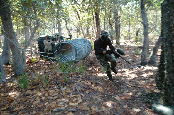 Senior Airman Brendan Harms, 96th Security Forces Squadron investigator, races to find cover as members of his team provide cover fire during a game of paintball against students from the youth center. The investigations Airmen want to curb mischievous behavior in adolescents on base by becoming their mentors before those acts become criminal in nature. (Air Force photo by Staff Sgt. Mike Meares)