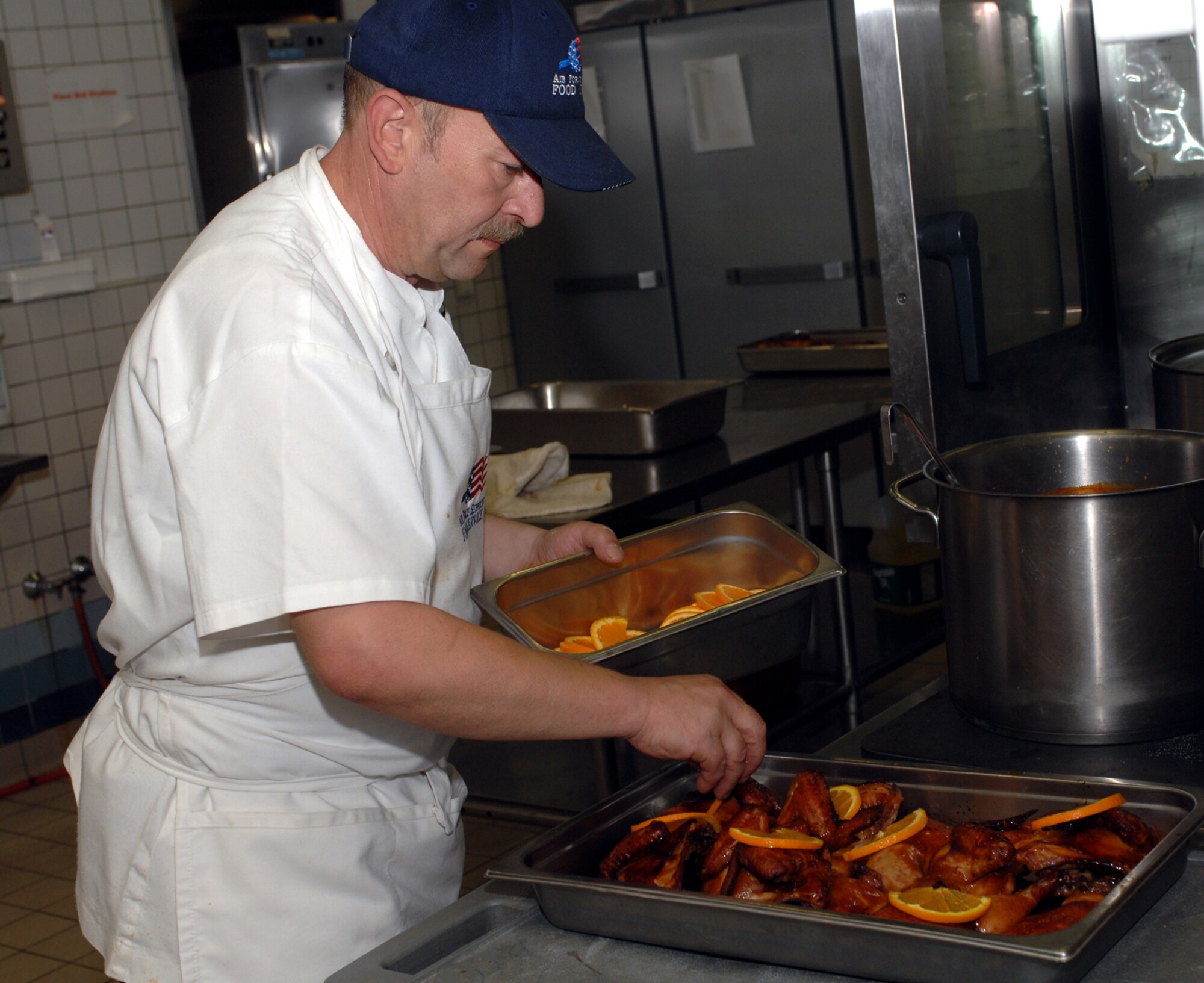 SPANGDAHLEM AIR BASE, GERMANY -- Local National Walter Vrzal prepares baked chicken as part of a nutritious lunch time experience at the Mosel Dining Facility here June 5, 2007. (U.S. Air Force photo/Airman 1st Class Stephanie Clark) 