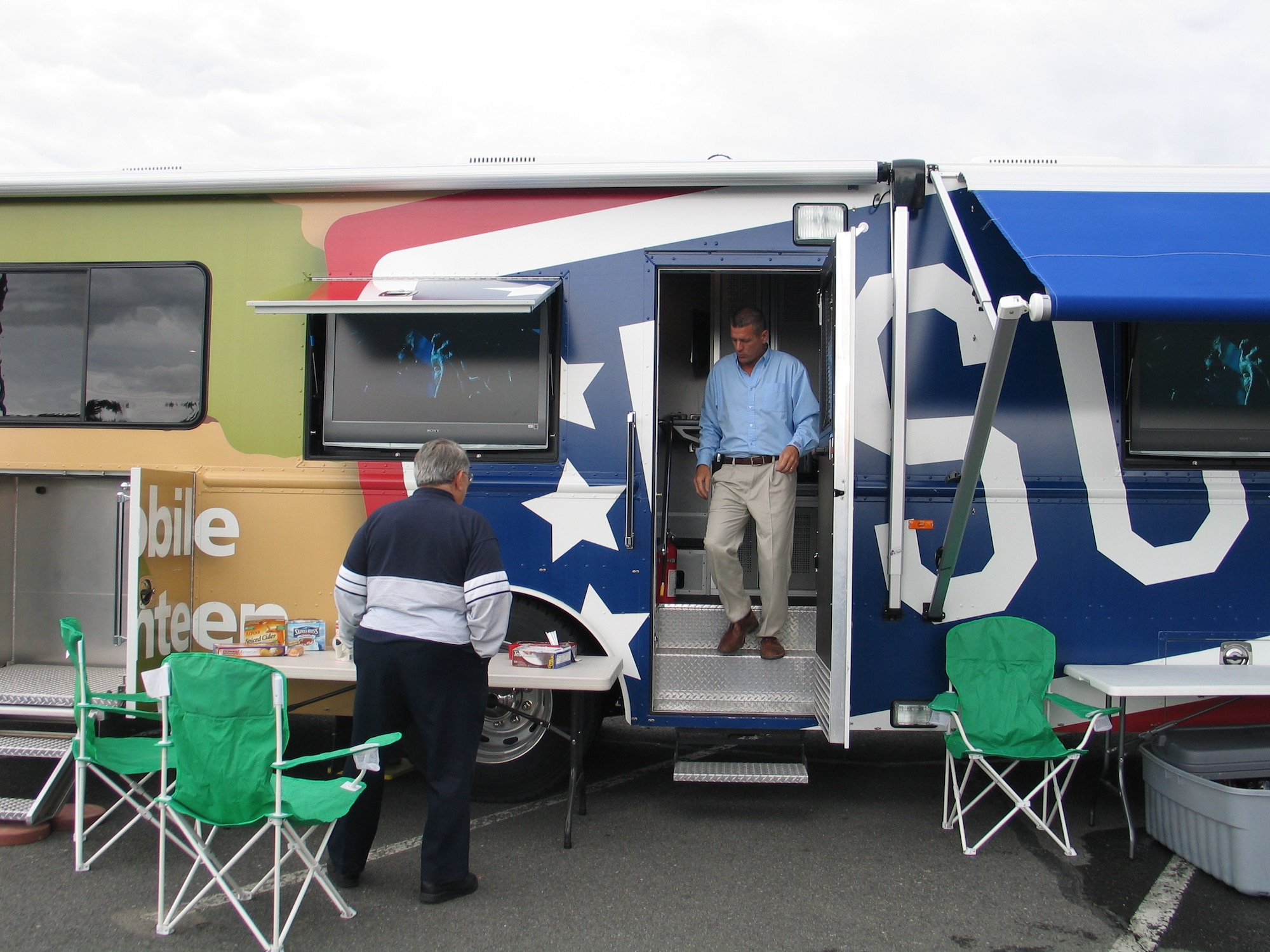 FAIRCHILD AIR FORCE BASE, Wash. -- Corey Hulse, United Services Organization, helps a customer at the USO mobile canteen at the BX parking lot June 5. The canteen is designed to bring USO programs directly to stateside servicemembers. There are ten mobile canteens worldwide; three of those are dedicated to the United States. (U.S. Air Force photo/Staff Sgt. Connie L. Bias)
