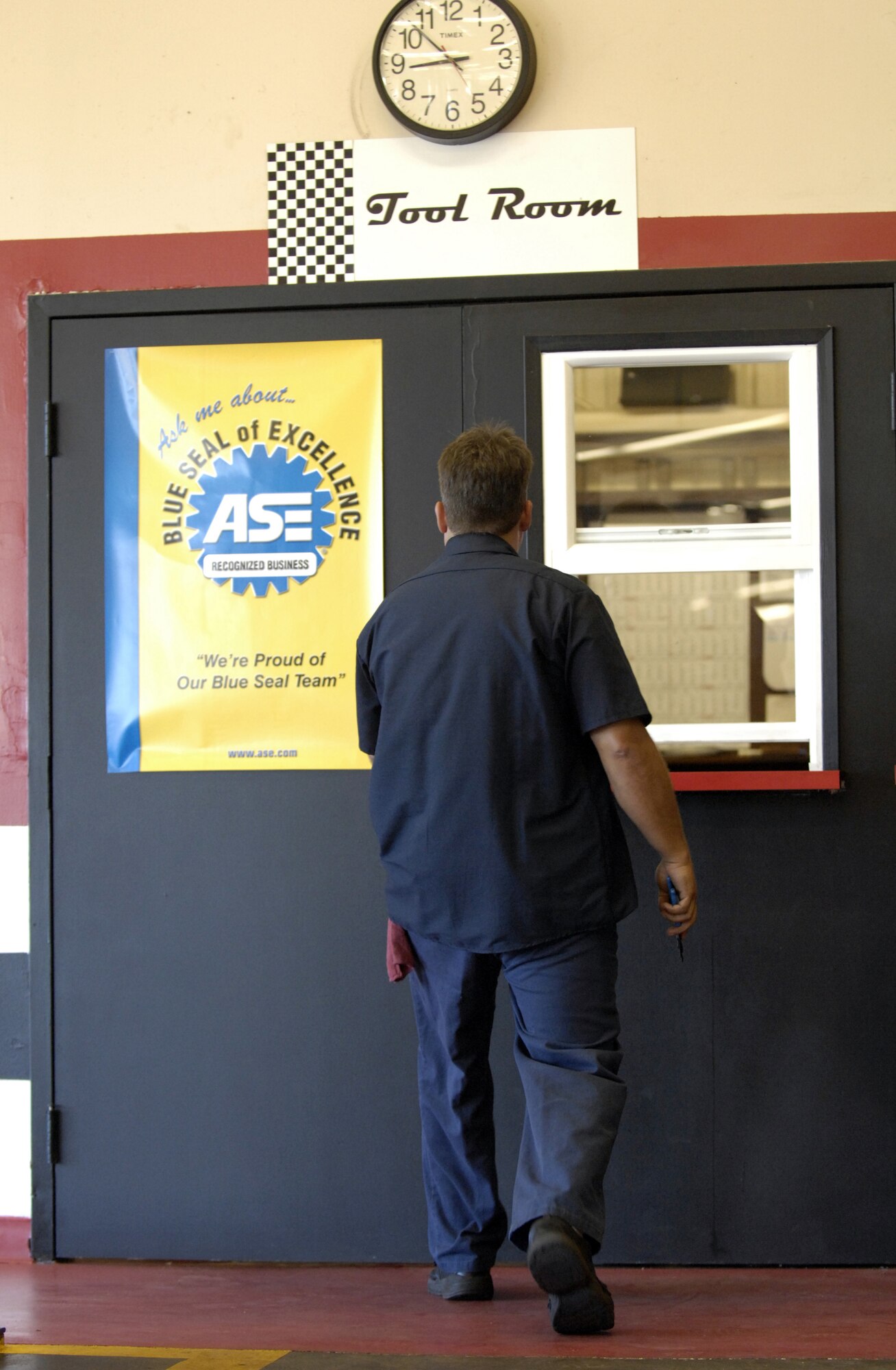 Andy Martin walks past a Blue Seal of Excellence poster on the way to the tool room at the Auto Skills Center on Hickam Air Force Base, Hawaii June 6. The Hickam Auto Skills Center was recently awarded the Blue Seal of Excellence from the National Institute for Automotive Service Excellence. The Blue Seal of Excellence recognition program’s emphasis is to identify establishments with a large percentage of ASE certified professionals and businesses striving to be the best and willing to prove their commitment to excellence. Andy is the Auto Skills Center manager. (USAF photo/ Tech. Sgt. Shane A. Cuomo)