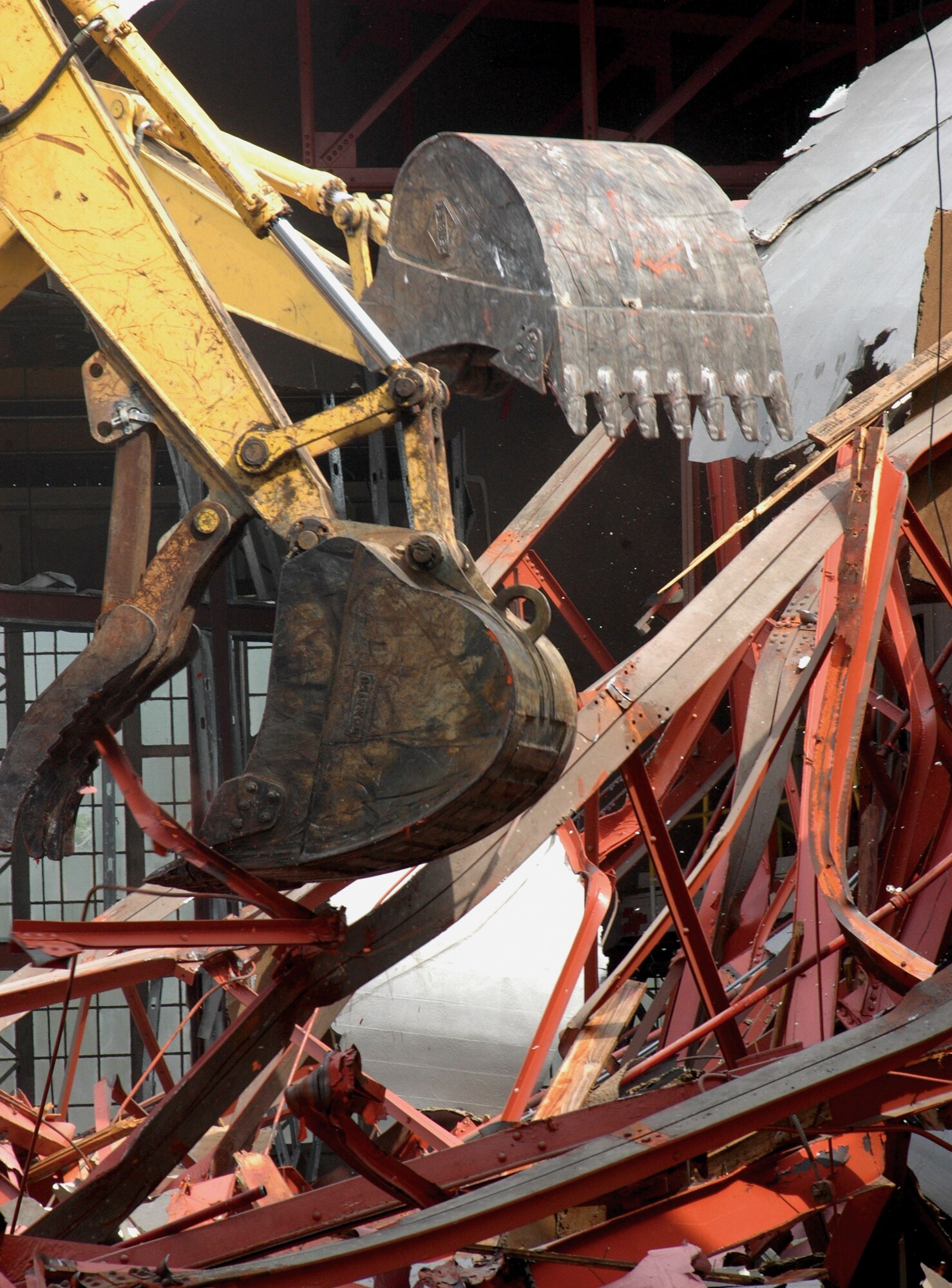 Excavators using a thumb to bite into solid pieces of the hangar. Tearing the building down was quick compared to the cleanup of the site which is still ongoing. (U.S. Air Force Photo/Senior Airman Tabitha Spinks)