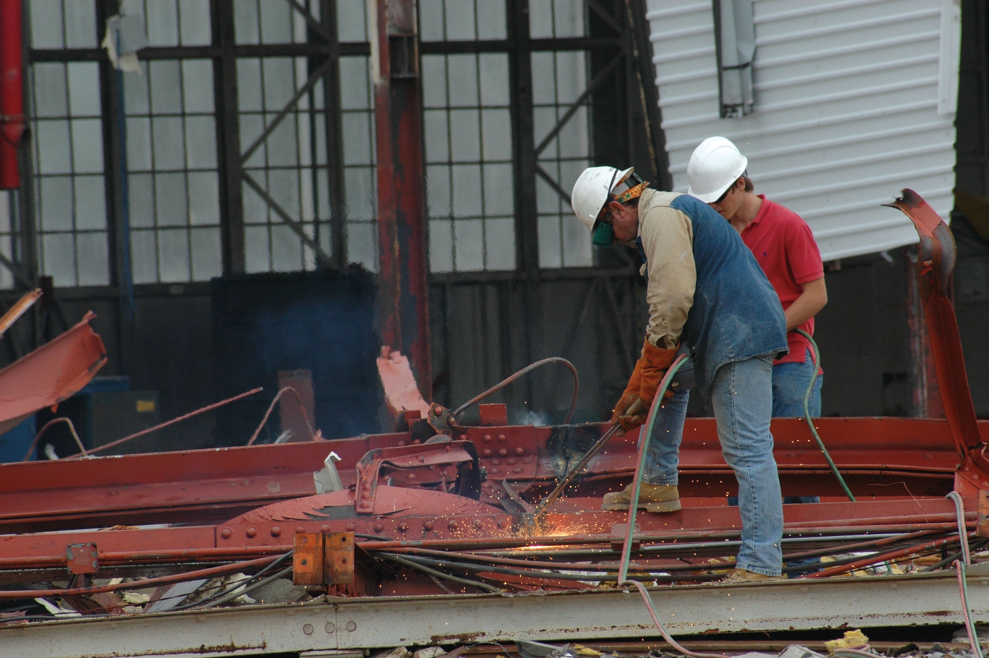 Sparks fly as workmen from Whitesell Green Inc. General Contractors use torches to break down large girders that made up the roof of Hangar 5. The historic building was demolished beginning in April. (U.S. Air Force Photo/Senior Airman Tabitha Spinks)
