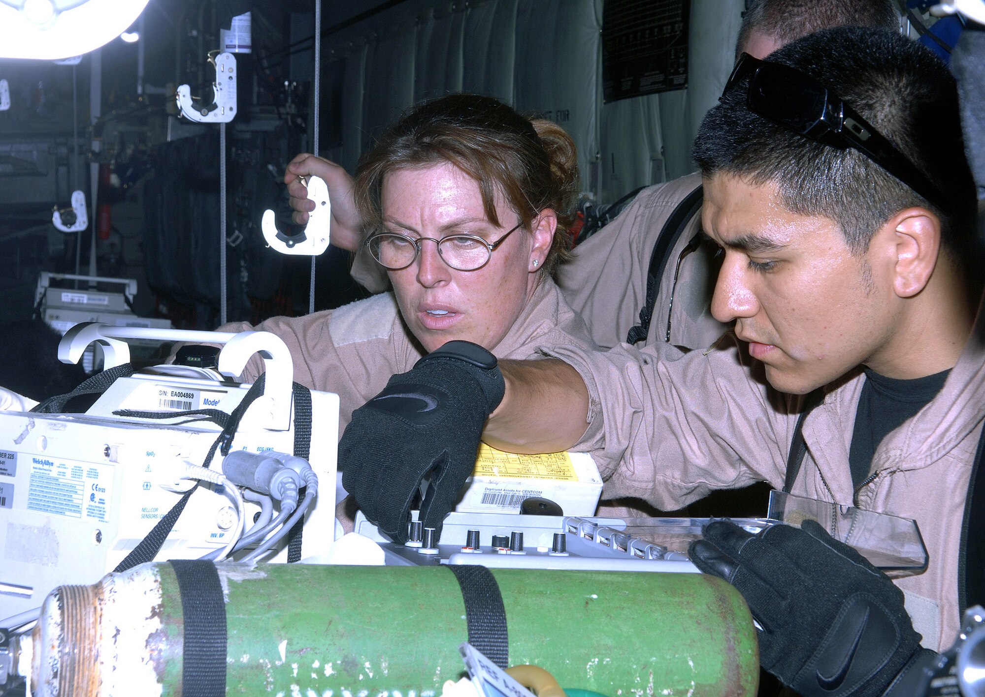 Capt. Jenna Jamison (left), critical care air transport team intensive care nurse, and Senior Airman Roy Aguilar, CCATT respiratory therapist, stabilize a critical patient after loading him on a C-130 bound for Bagram Airfield, Afghanistan June 5. Capt. Jamison and Airman Aguilar are deployed from Wilford Hall Medical Center, Lackland Air Force Base, Texas. (photo by Staff Sgt. Craig Seals)