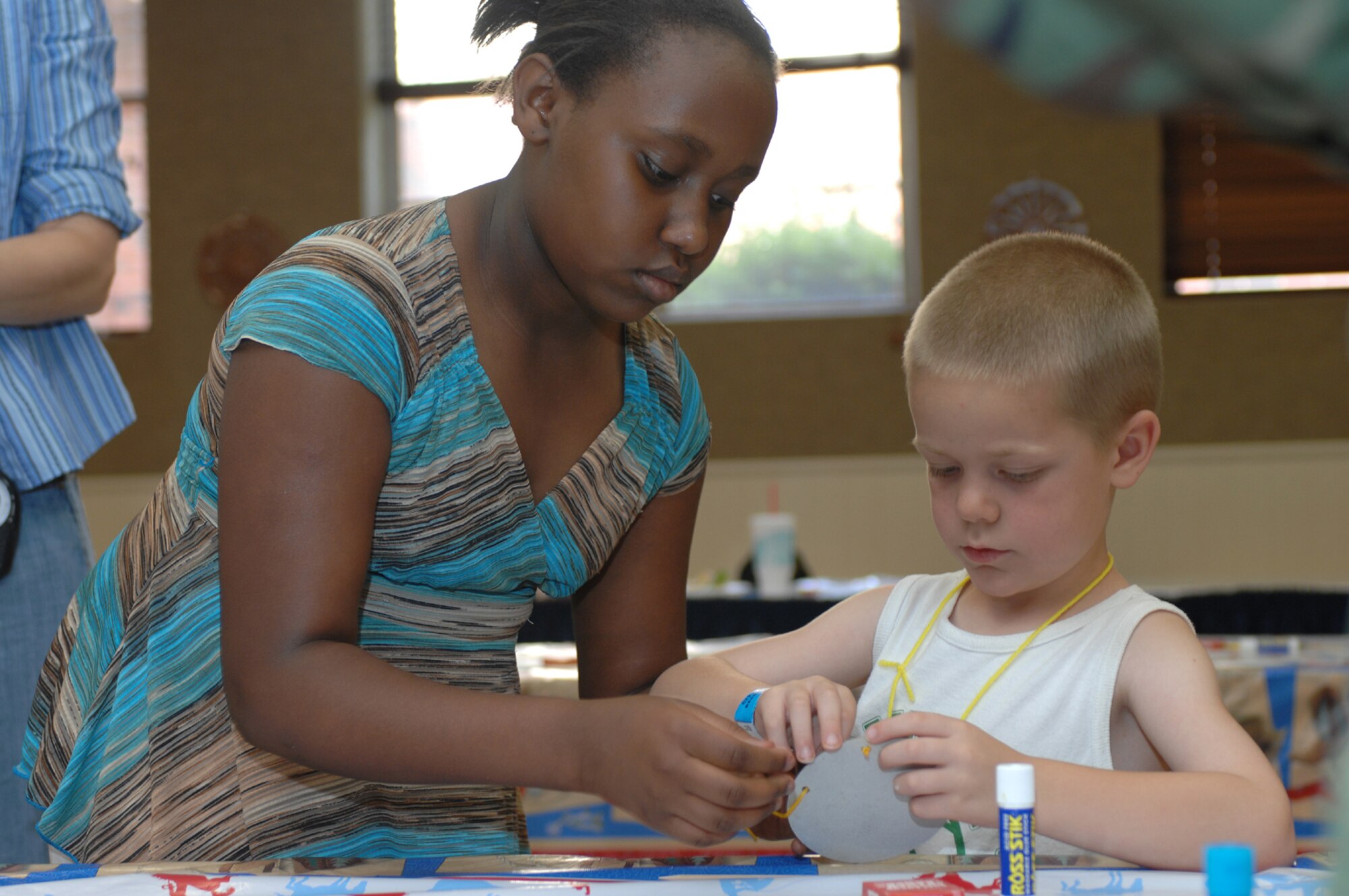 DYESS AIR FORCE BASE, Texas -- Tajninque Bottom (left) helps Conner Stimmle with his arts and crafts project at Vacation Bible School at the chapel June 6. During the course of the day, children do various activities to learn Bible lessons in a fun way. (U.S. Air Force photo by A1C Jennifer Romig)