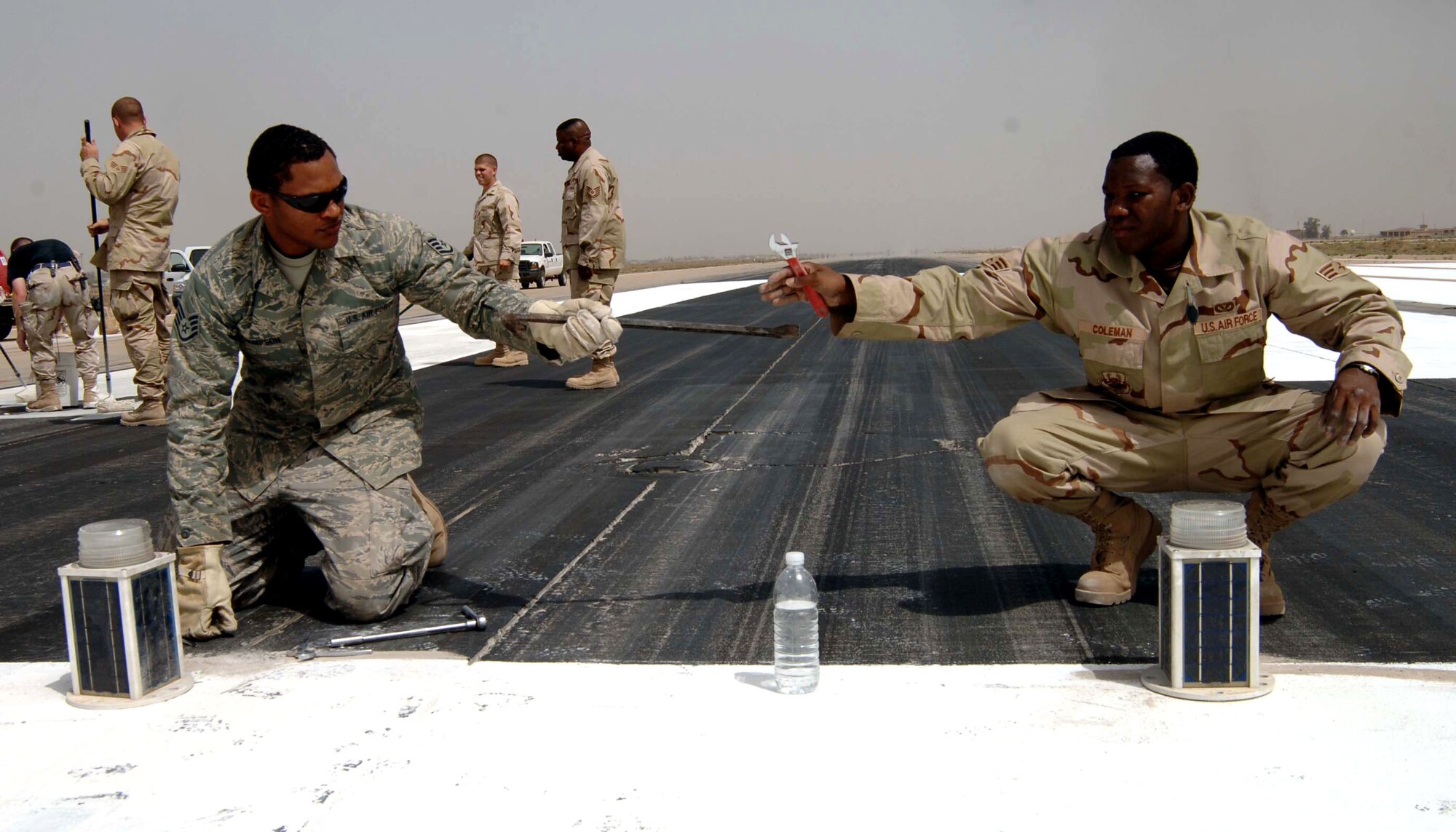Staff Sgt. Charles Thompson (left) and Senior Airman Tremelle Coleman work together to install threshold lights on the Baghdad International Airport runway May 30 in Iraq. These threshold lights are being installed temporarily to shorten the runway by 3,000 feet so repairs can be made. Sergeant Thompson and Airman Coleman are 447th Expeditionary Civil Engineer Squadron electricians. (U.S. Air Force photo/Tech. Sgt. Russell Wicke)
