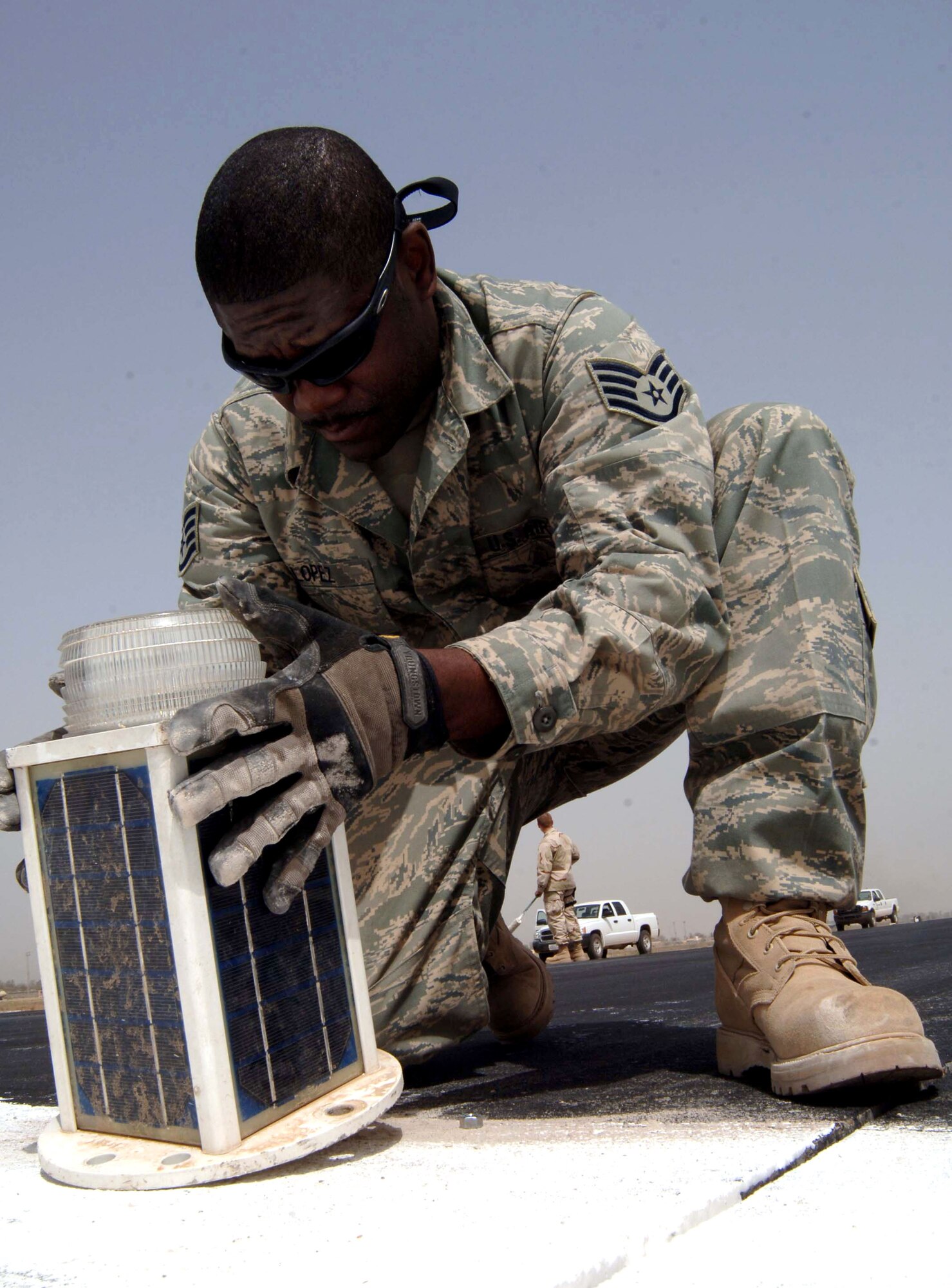 Staff Sgt. Larry Lopez positions a threshold light on the Baghdad International Airport runway May 30 in Iraq. These threshold lights are being installed temporarily to shorten the runway by 3,000 feet so repairs can be made. Sergeant Lopez is a 447th Expeditionary Civil Engineer Squadron electrician. (U.S. Air Force photo/Tech. Sgt. Russell Wicke)
