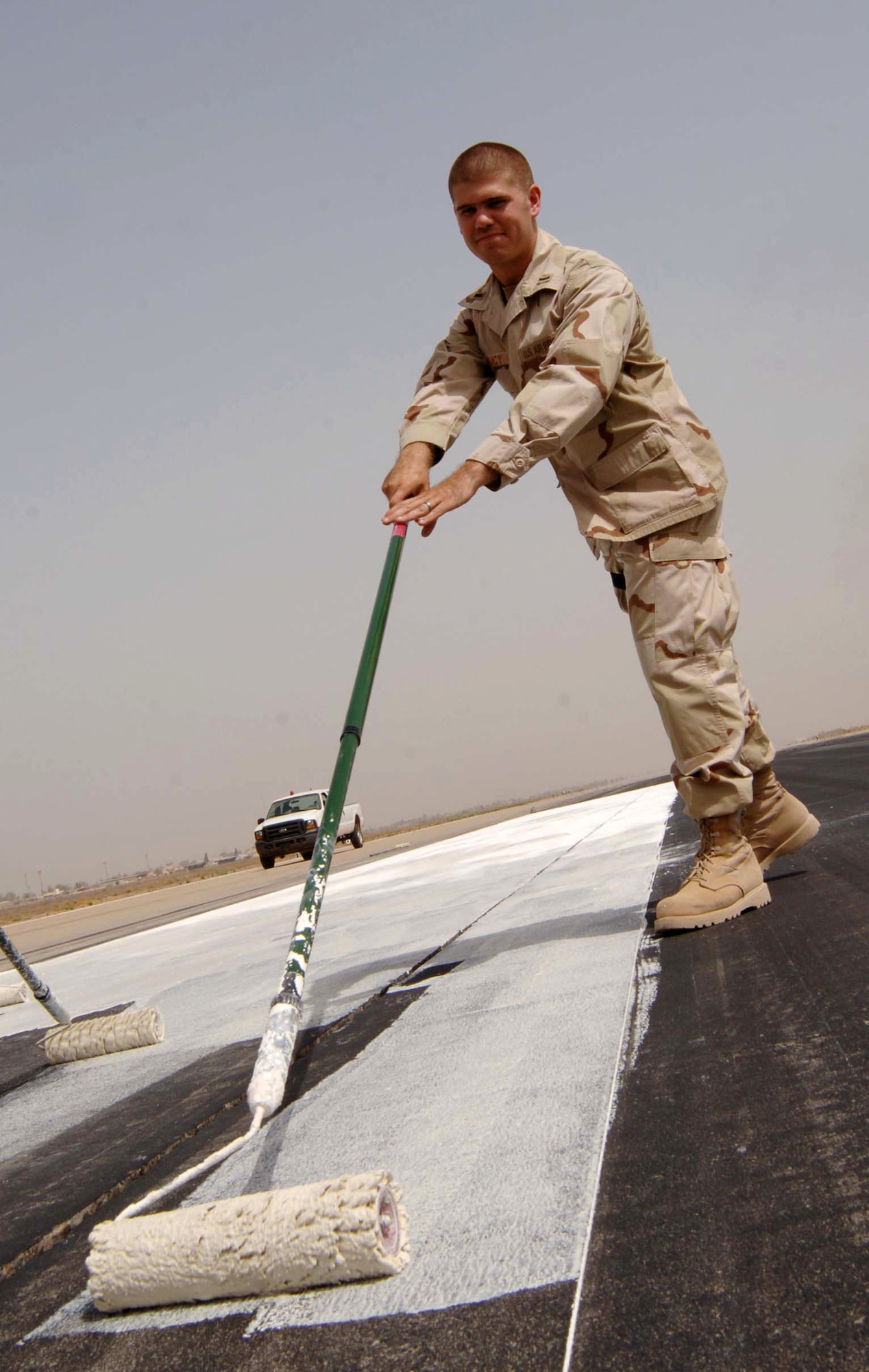 1st Lt. Stephen Bucy paints a liquid lime mixture on the runway May 30 at Baghdad International Airport in Iraq. The lime acts as temporary markings for the shortening of the runway so repairs can be made. The runway was shortened by 3,000 feet. Lieutenant Bucy is assigned to the 447th Expeditionary Civil Engineer Squadron. (U.S. Air Force photo/Tech. Sgt. Russell Wicke)
