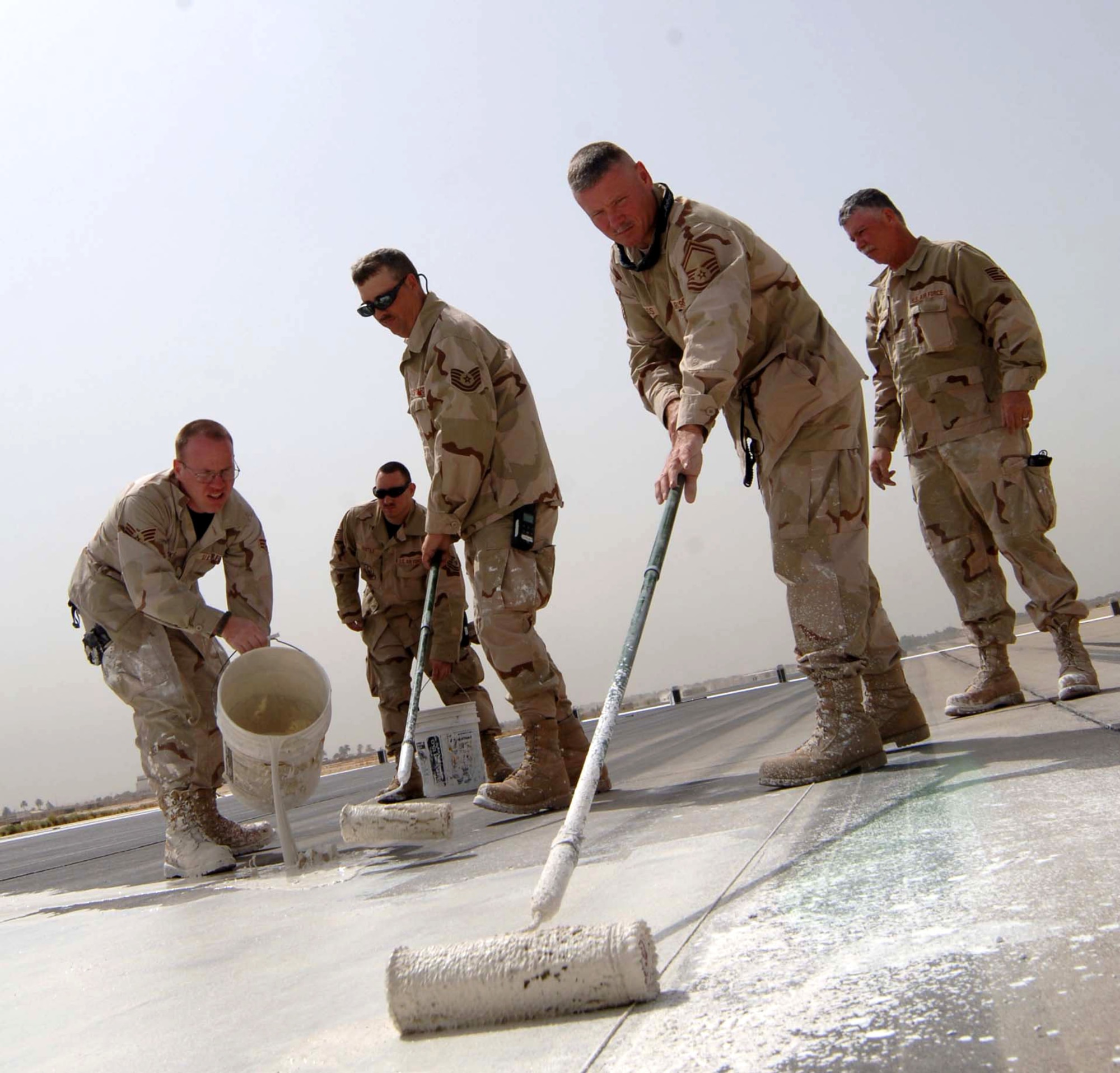 Airmen from the 447th Expeditionary Civil Engineer Squadron paint a liquid lime mixture on the runway May 30 at Baghdad International Airport in Iraq. The lime acts as temporary markings for the shortening of the runway so repairs can be made. The runway was shortened by 3,000 feet. (U.S. Air Force photo/Tech. Sgt. Russell Wicke)

