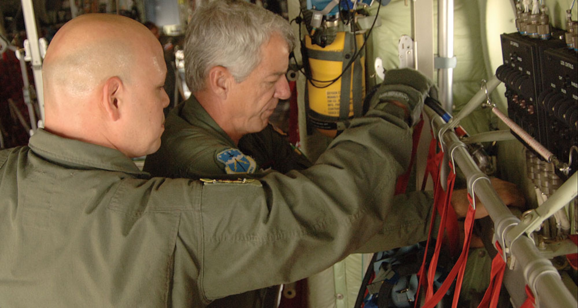 Tech. Sgt. Mark Juarez, 433rd Aeromedical Evacuation Squadron, (foreground) gets assistance from Chief Master Sgt. Robert Lee, weather reconnaissance loadmaster, of the Hurricane Hunters, in accessing connections on a WC-130J. In addition to flying into hurricanes and other tropical weather, Lee and the 53rd Weather Reconnaissance Squadron also fly airlift missions such as transporting vehicles and equipment, as well as supporting training and real-world aeromedical missions. (U.S. Air Force Photo/Tech. Sgt. James B. Pritchett)