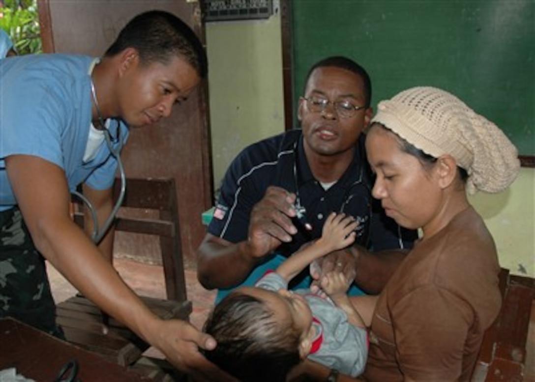 U.S. Navy Lt. j.g. Melvin Pruitt (center) examines a child with the aid of Philippine Navy Petty Officer 3rd Class Norman Sanico (left) during a medical civic action project in Isabela, Philippines, on June 2, 2007.  The project is being conducted as part of the Cooperation Afloat Readiness and Training exercise, an annual series of bilateral maritime training exercises between the United States and six Southeast Asian nations designed to build relationships and enhance the operational readiness of the participating forces.  
