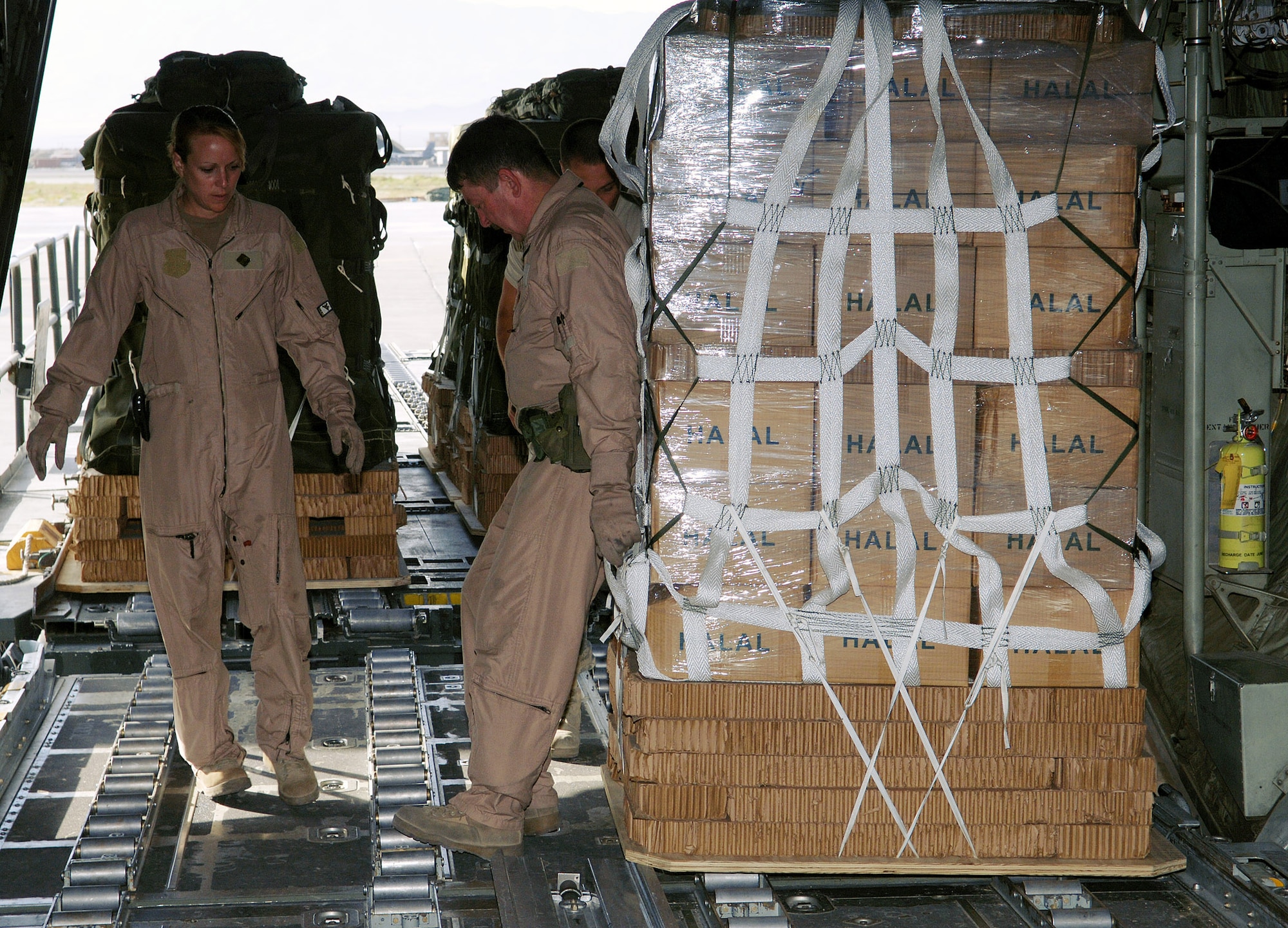Master Sgt. Jennifer Dunaway (left) and Senior Master Sgt. Doug Walton, 774th Expeditionary Airlift Squadron loadmasters, load pallettes filled with supplies onto their C-130 prior to an airdrop mission at Bagram Airfield, Aghanistan. Sergeants Dunaway and Walton are deployed from the 130th Airlift Wing, West Virginia National Guard. (photo by Staff Sgt. Craig Seals)
