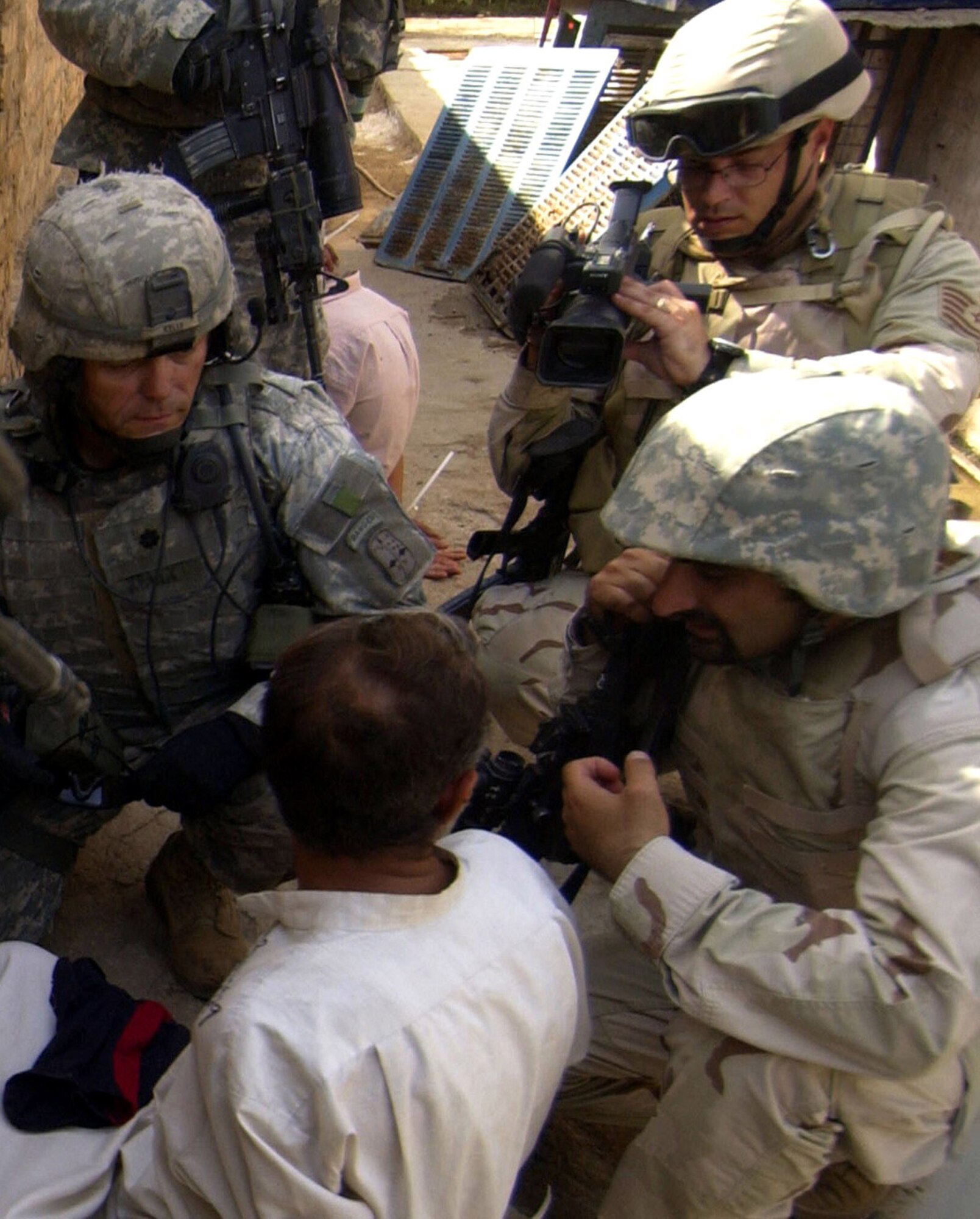 Tech. Sgt. Gary Burdett videotapes an Iraqi citizen being questioned by U.S. and Iraqi soldiers in Baghdad's Hamiyah district Aug. 13, 2006. A search of the Iraqi's house had yielded a quantity of unauthorized weapons. Sergeant Burdett is a member of 1st Combat Camera Squadron at Charleston Air Force Base, S.C. (U.S. Air Force photo/Tech. Sgt. Adrian Cadiz) 

