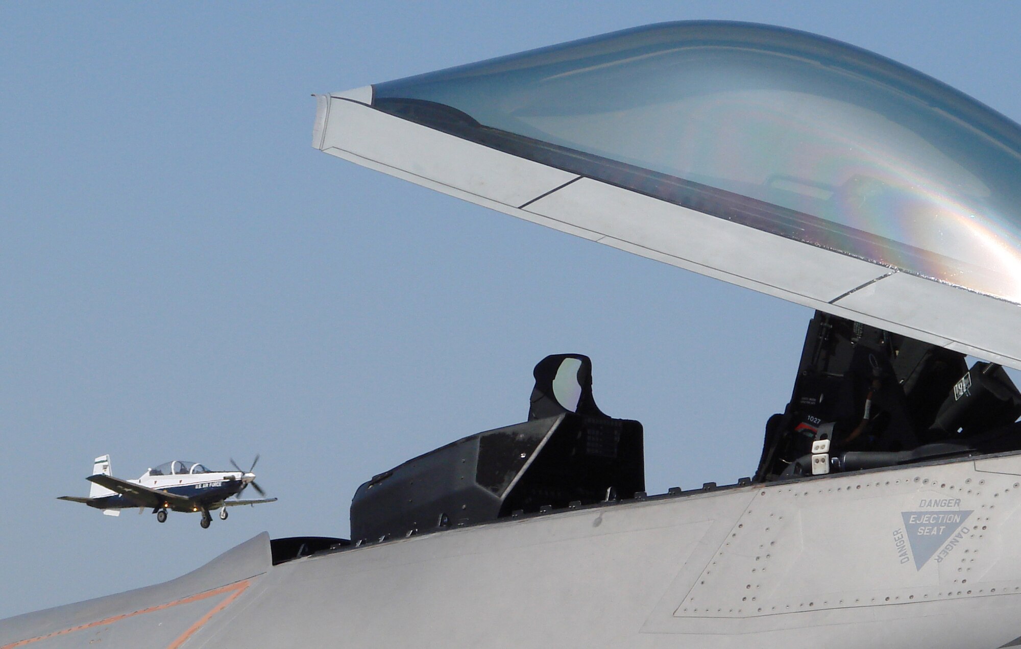 A F-22 Raptor parked on the ramp at Vance Air Force Base, Okla., Friday, appears to be taking its bird of prey name literally and is prepared to feast on a T-6 Texan II taking off on a nearby runway. The Raptor, from Tyndall AFB, Fla. was flown by Maj. "Mooch" Bartels, 325th Operations Group. Major Bartels took time during his brief refueling stop to talk to some of the students and instructor pilots assigned to the Joint Specialized Undergraduate Pilot Training base. (U. S. Air Force photo by Frank McIntyre)                