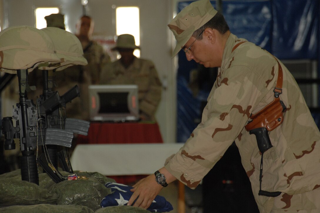 Major Michael Howard, Air Force Office of Special Investigations Expeditionary Detachment 2410 commander, presents a flag during a memorial ceremony honoring Special Agents Ryan Balmer and Matthew Kuglics at Kirkuk Regional Air Base, Iraq, June 8, 2007. The agents were killed in action June 5 while supporting Operation Iraqi Freedom. (U.S. Air Force photo/ Senior Airman Kristin Ruleau)