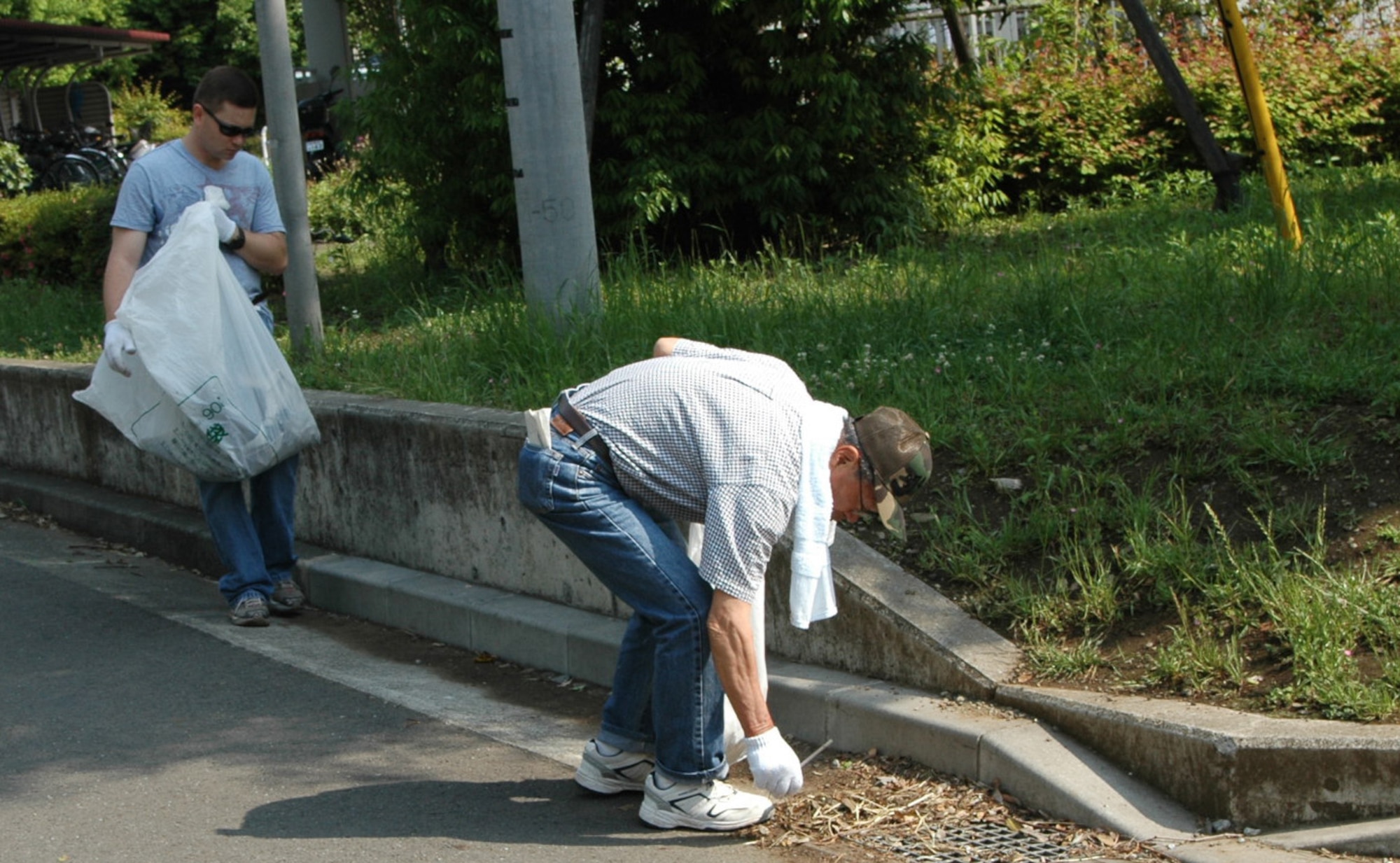 Maj. Timothy Bunnell, 374th Logistics Readiness Squadron, and Shiochi Kurihara, president of the Mizuho- Yokota Friendship Association, are collectin trash off the street during the 25th Mizuho Town Annual Cleanup. (Photo by Airman 1st Class Eric Summers VIRIN 070604-F-9864S-022)