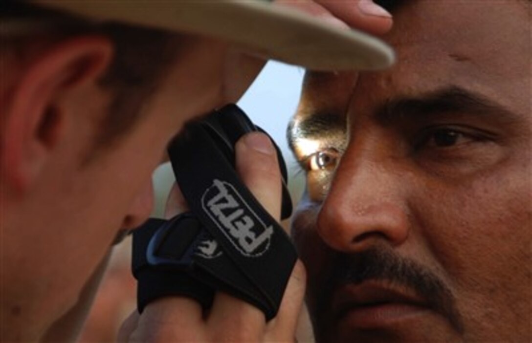 A U.S. Navy sailor examines the eye of an Iraqi army soldier during training with coalition forces near Baghdad, Iraq, on May 29, 2007.  