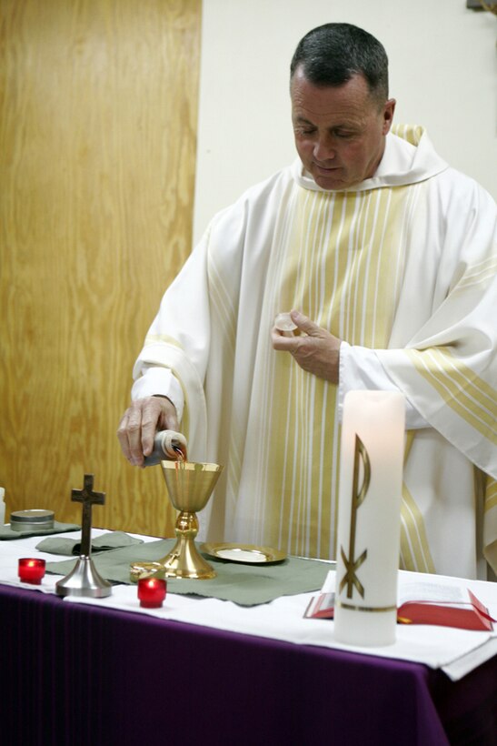 CAMP AL QA'IM, Iraq- Naval Commander Dennis Rocheford, a Catholic chaplain with II Marine Expeditionary Force, fills a goblet symbolizing "the blood of Christ" during the Eucharist at St. Michael's Chapel.  Rocheford is a former Marine during the Vietnam Conflict.