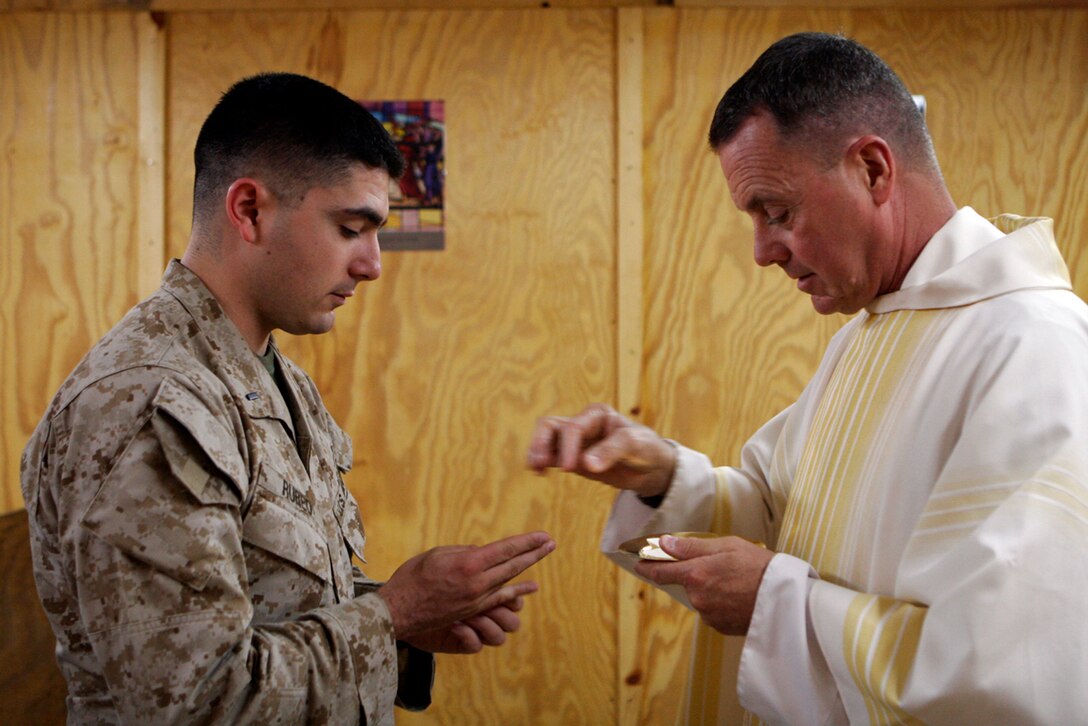 CAMP AL QA'IM, Iraq- Naval Commander Dennis Rocheford, a Catholic chaplain with II Marine Expeditionary Force, serves communion to 1stLt. Steven Rubeo, a supply officer with Headquarters and Support Company, Task Force 1st Battalion, 4th Marines at the St. Michael's Chapel.  Rocheford, a former Marine during the Vietnam Conflict, feels "Marines are the finest people I know."