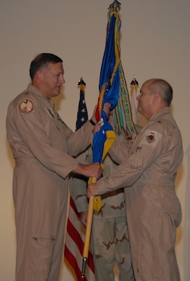 Lt. Gen. Gary North, U.S. Central Command Air Force commander (left), passes the 379th Air Expeditionary Wing guidon to incoming commander Brig. Gen. Charlie Lyon. General Lyon assumed command of the 379th AEW Tuesday.