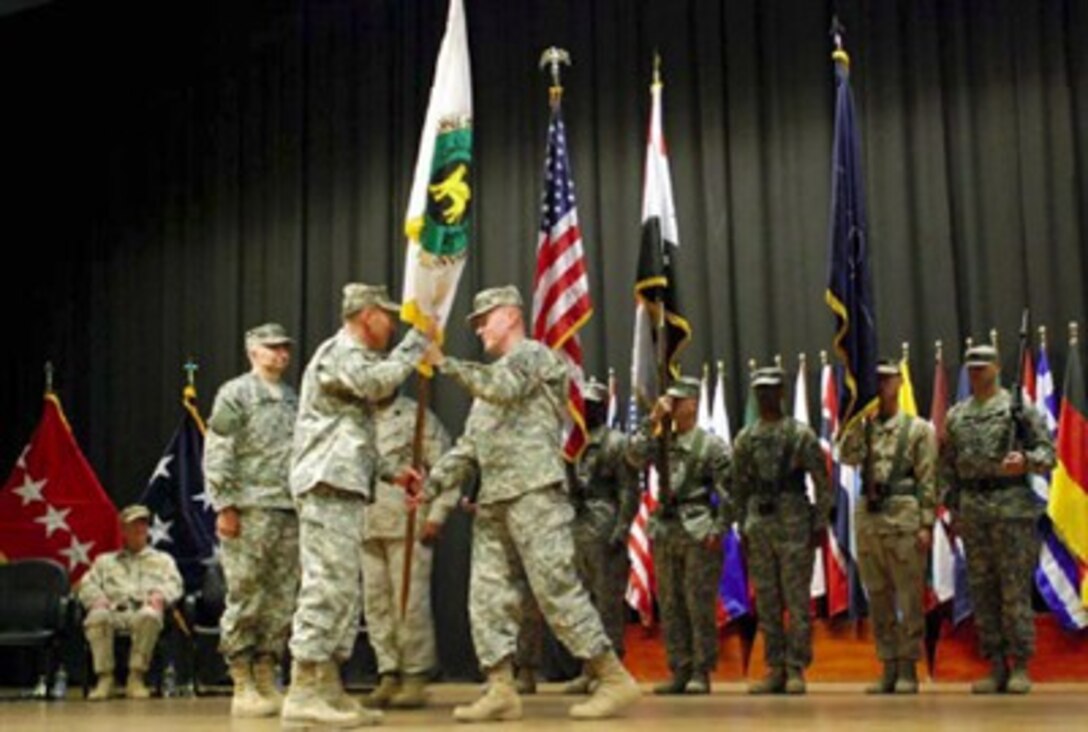 U.S. Army Lt. Gen. Martin E. Dempsey, outgoing commander of Multi-National Security Transition Command - Iraq, passes the unit colors to U.S. Army Gen. David H. Petraeus, commander of Multi-National Force - Iraq, left, during a change of command ceremony, June 10, 2007.
