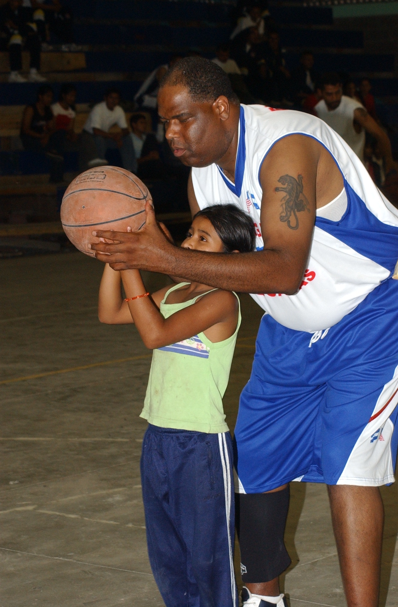 Army Sgt. Alonzo Lunsford, a member of the Soto Cano Air Base basketball team, the Comayagua Iguanas, shows the proper shooting technique to young Honduran girl June1 in Siguatepeque, Honduras. Sergeant Lunsford is a player and coach for the base team. The team receives invitations to travel and play local Honduran teams. Sgt. Lunsford says the games offer a key avenue to bridge the cultural gaps between Americans and Hondurans. U.S. Air Force photo by Senior Airman Shaun Emery.