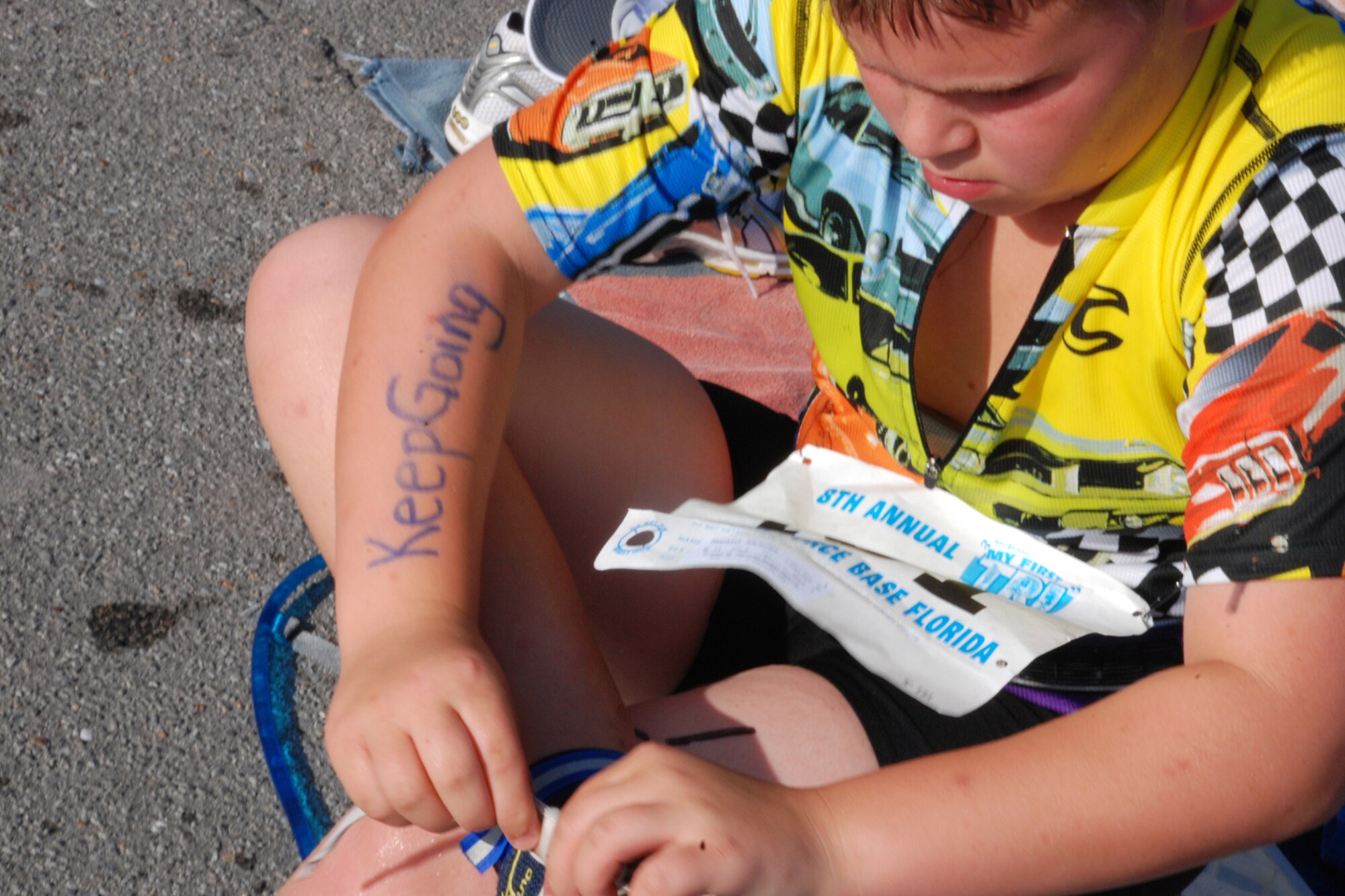 EGLIN AIR FORCE BASE, Fla. -- Nick Hopkins, 11, of Shalimar Fla., puts on his shoes after the 200-meter swim at the 8th Annual My First Tri triathlon at Post'l Point June 9. He had "Eat my bubbles...tread...dust" written in marker on his back and a reminder on his right arm that read "Keep Going." The triathlon featured a 8-mile bike ride and 2.5-mile run after the 200-meter swim. A total of 150 out of the 248 triathletes were participating in their first triathlon. (U.S. Air Force Staff Sgt. Mike Meares)