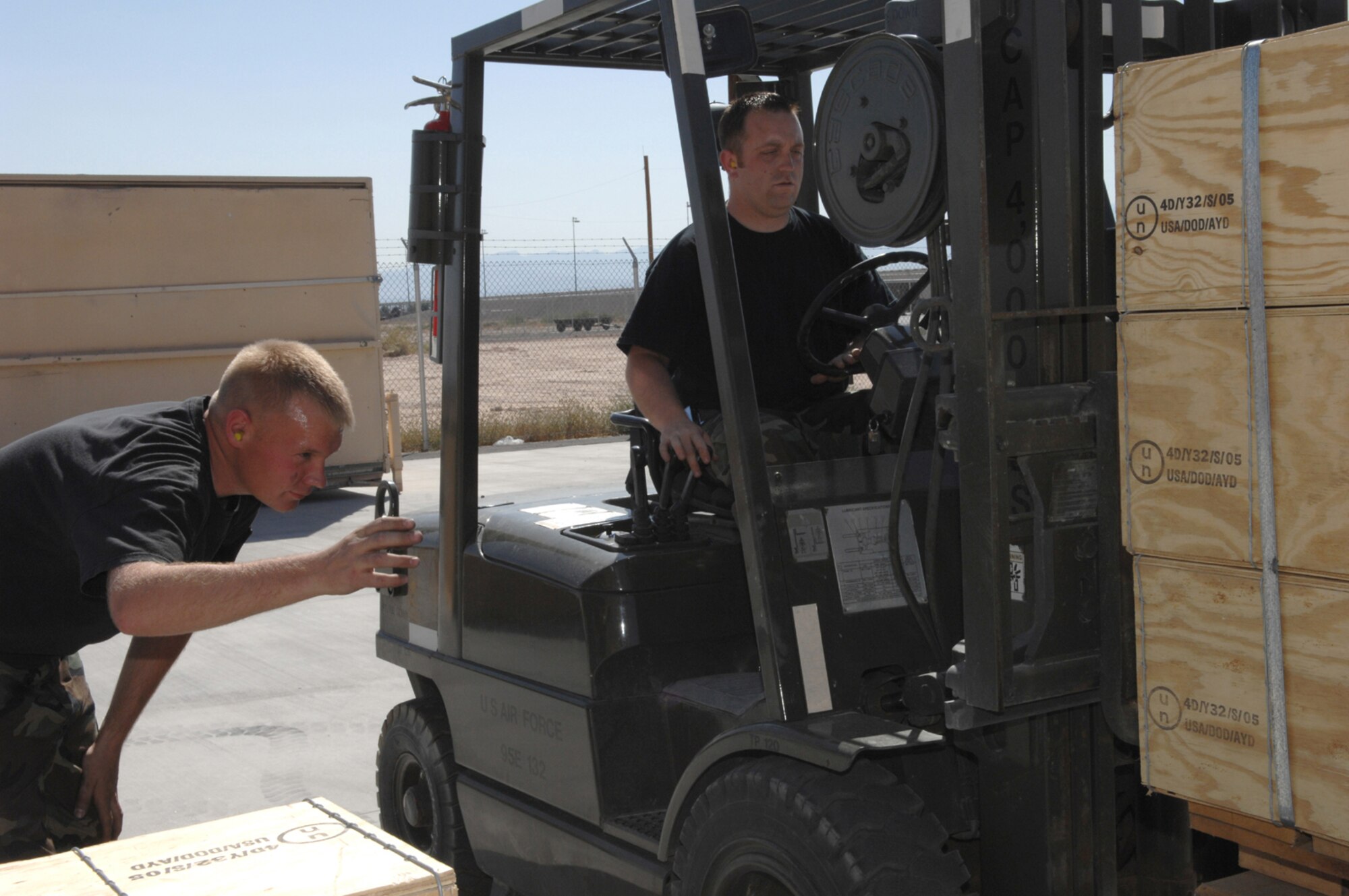 United States Air Force Staff Sergeants Byron Edwards (spotter) and Trevor McKinley, both line delivery crew chiefs assigned to the 57th Equipment Maintenance Squadron's Munitions Flight, prepares to transfer a pallet to store Tuesday May 15, 2007 Nellis Air Force Base, Nevada.(U.S Air Force Photo by/ Senior Airman Larry E. Reid Jr.)