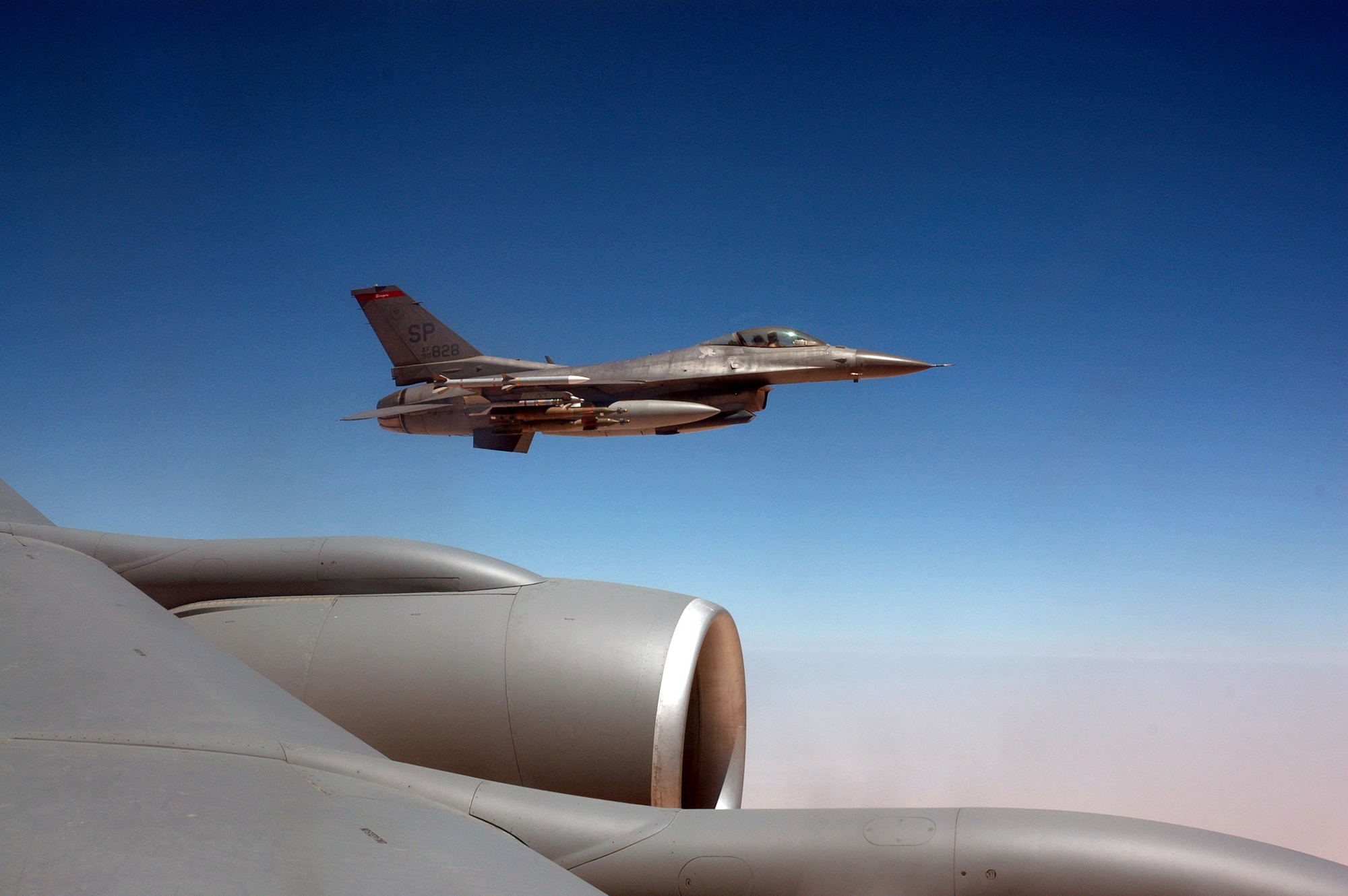 An F-16 Fighting Falcon flies beside a KC-135 Stratotanker after receiving fuel.  Coalition tankers offloaded 2.7 million pounds of fuel, the equivalent of 403,000 gallons of automobile fuel, to 224 coalition aircraft June 9.  (U.S. Air Force photo.)