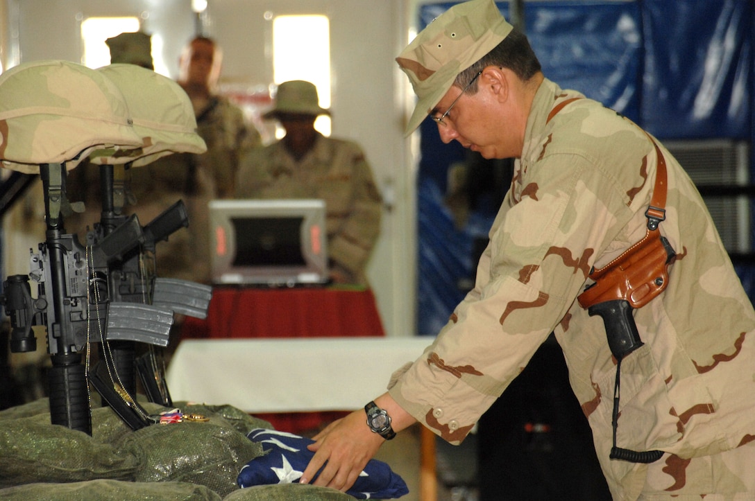 Maj. Michael Howard, the Air Force Office of Special Investigations Expeditionary Detachment 2410 commander, presents a flag during a memorial ceremony June 8 honoring Special Agents Tech. Sgt. Ryan Balmer and Staff Sgt. Matthew Kuglics at Kirkuk Regional Air Base, Iraq. The agents were killed in action June 5 while supporting Operation Iraqi Freedom. (U.S. Air Force photo/ Senior Airman Kristin Ruleau) 
