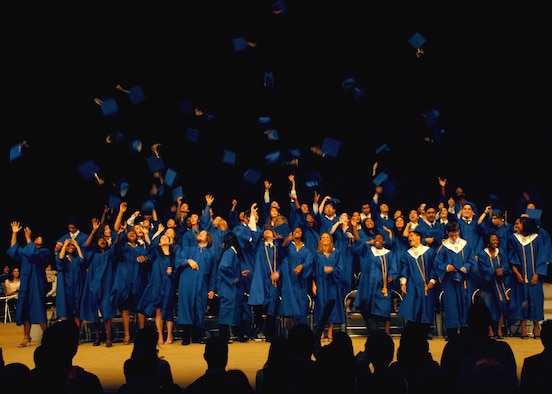 Seniors from Yokota High School, Japan, celebrate by tossing their graduation caps in the air on Jun. 7; at the Fussa City Community Center.