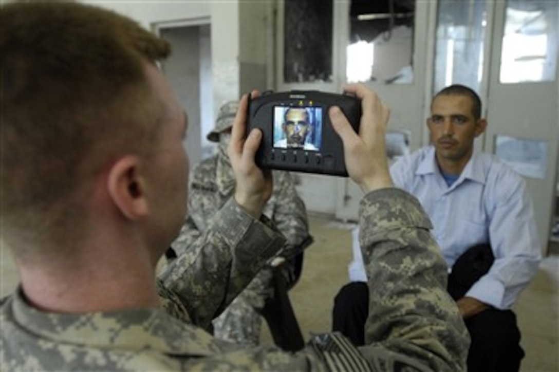 A U.S. Army soldier uses handheld interagency identity detection equipment to fingerprint and photograph new Iraqi police recruits at the Iraqi Police Academy in Mahmudiyah, Iraq, on May 30, 2007.  The soldier is from the 2nd Squad, 1st Platoon, 23rd Military Police Company, 89th Military Police Brigade.  