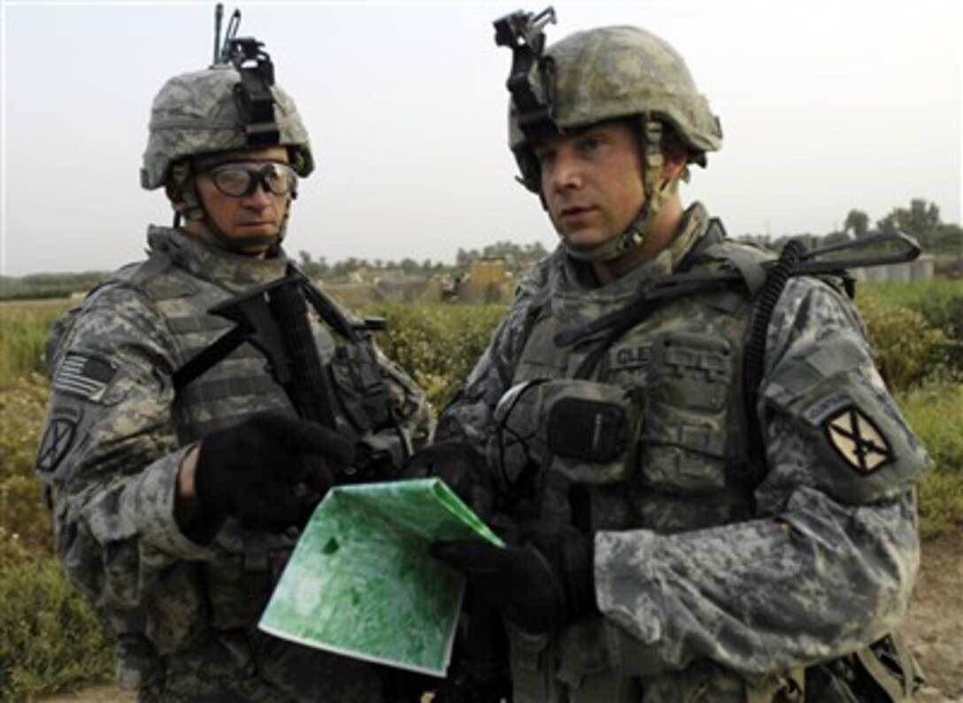 U.S. Army 1st Lt. Britt Cleveland (right) and Sgt. 1st Class Michael Carlan both from Alpha Battery, 2nd Battalion, 15th Field Artillery, 2nd Brigade Combat Team look over a map to recheck the grid coordinates of their assigned target during a dismounted patrol in Mahmudiyah, Iraq, on June 2, 2007.  