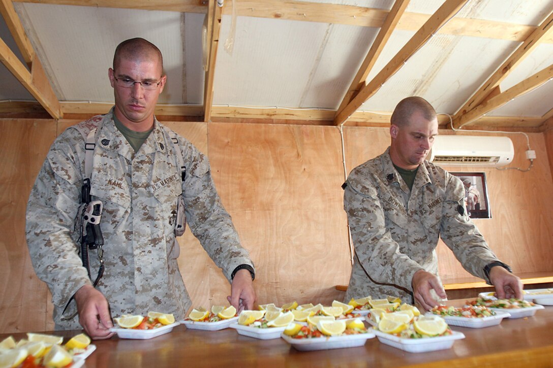 COMBAT OUTPOST RAWAH, IRAQ – (left to right) Staff Sgt. Barrett A. Kahl, the battalion field food service system chief with 1st Light Armored Reconnaissance Battalion, Regimental Combat Team 2, and Staff Sgt. Robert J. Downing, the battalion’s mess chief, lay out vegetables in an eye-pleasing arrangement. The vegetables were served beside pita bread, lamb and chicken in an traditional Iraqi meal. Official Marine Corps Photo By Cpl. Ryan C. Heiser.